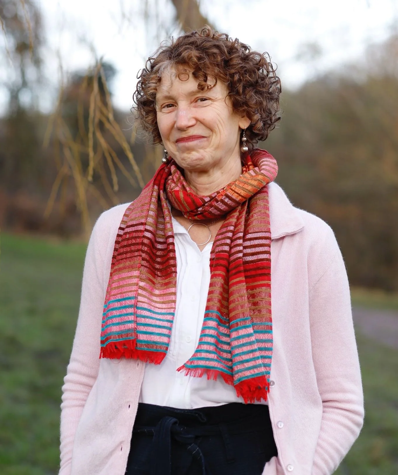 DavenLee.com - intimacy coach for women - bio photo of Daven in a green park with a colorful scarf. Smiling directly at the camera.