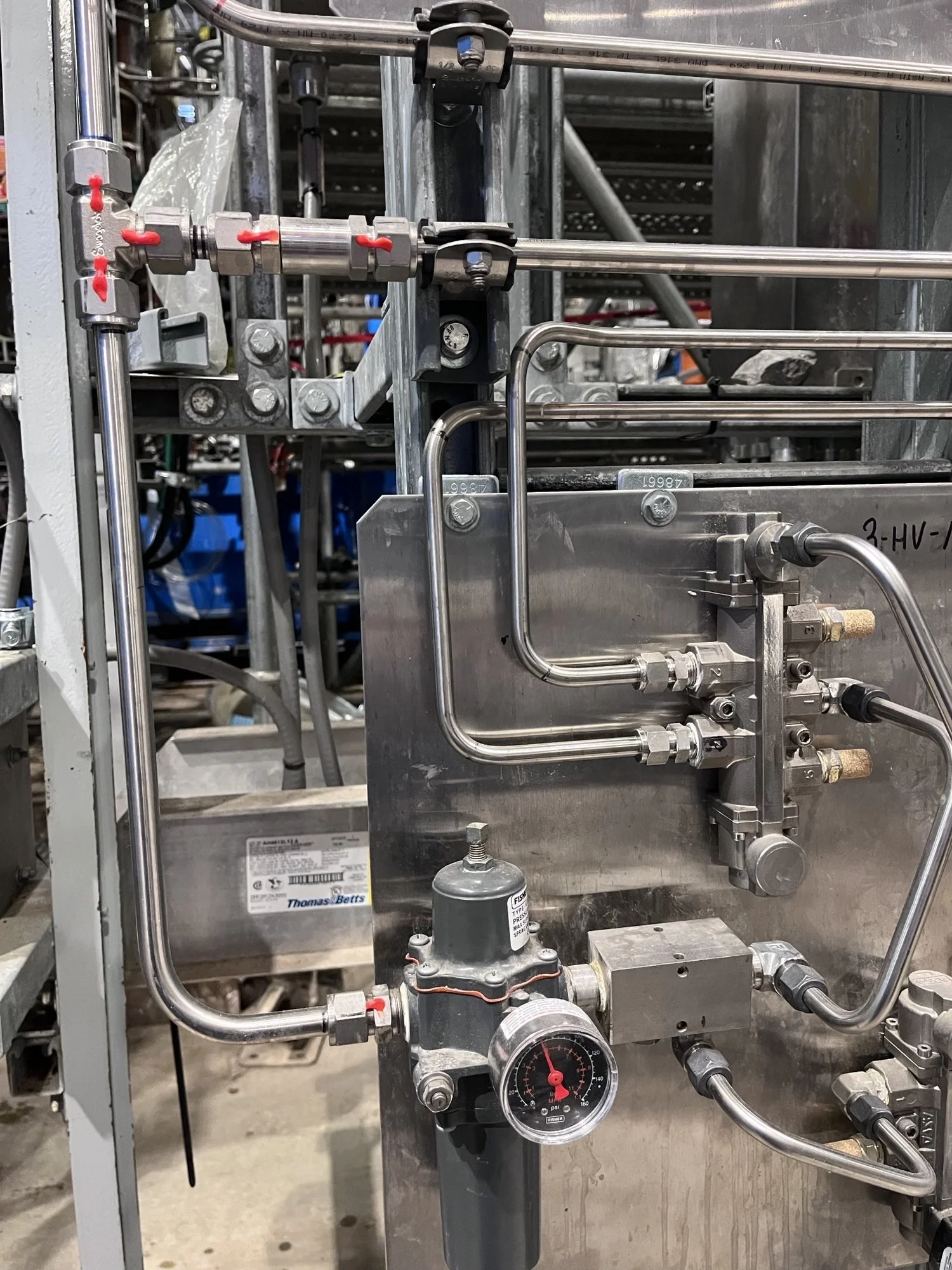 Close-up of industrial machinery with metal pipes, fittings, and a pressure gauge.