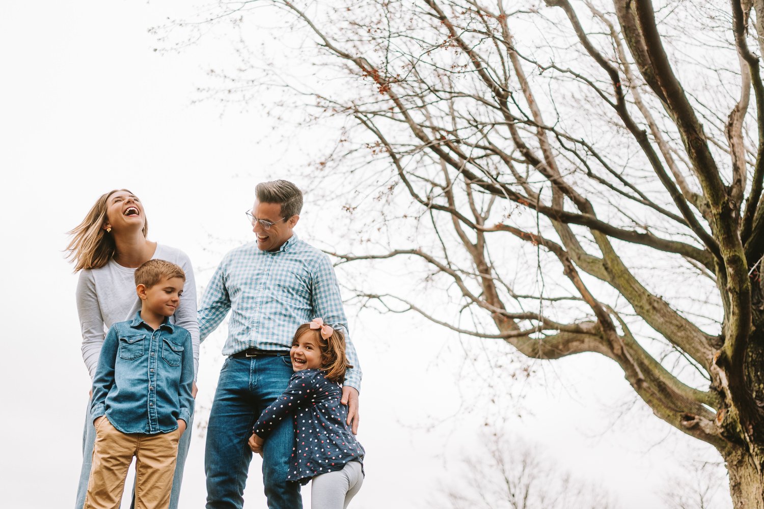 The Irvine family standing together in a park, holding hands and smiling during a relaxed outdoor photo session in Omaha, Nebraska.