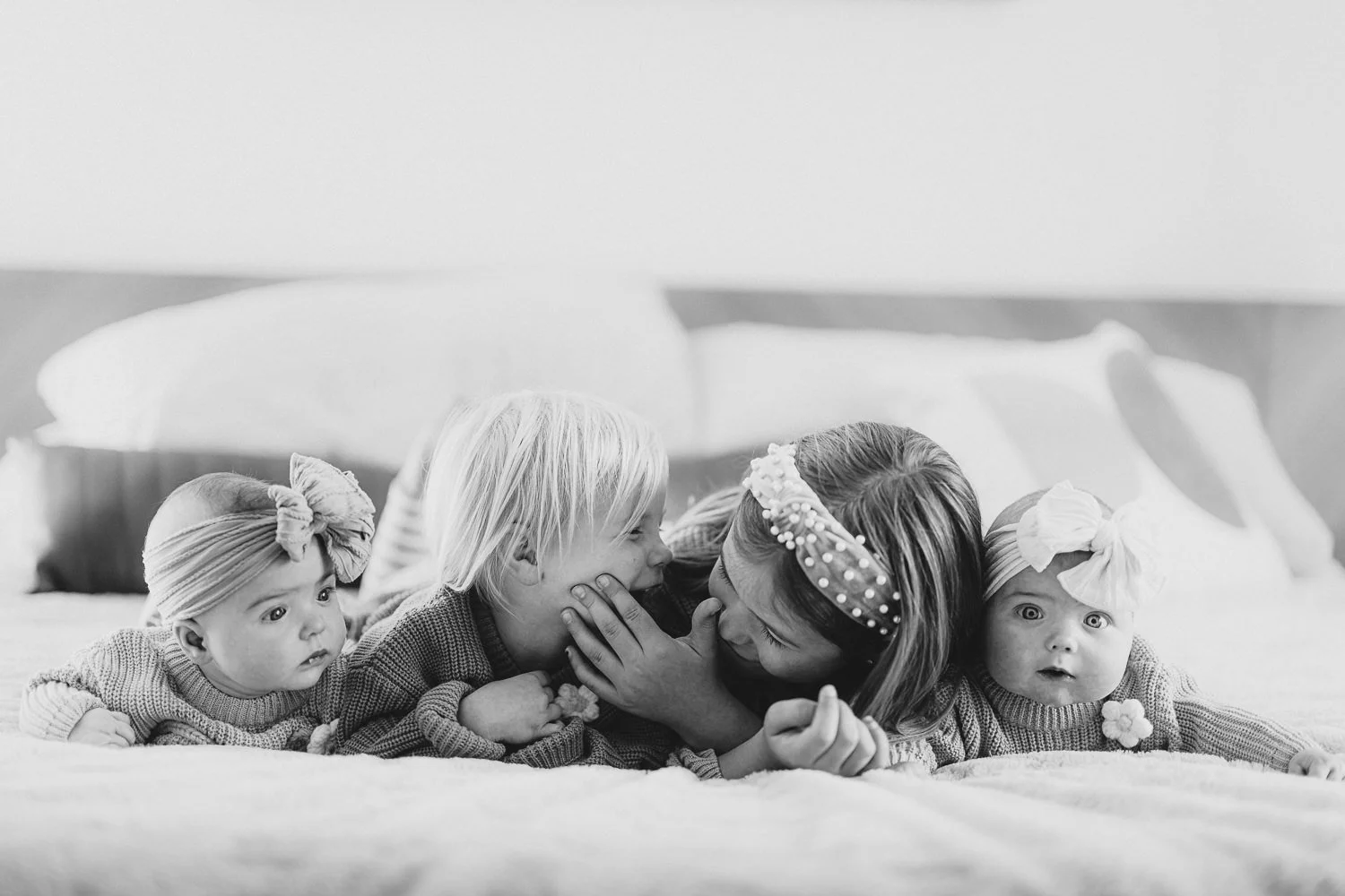 hildren laughing and snuggling on a bed at home during a Lincoln family photography session.