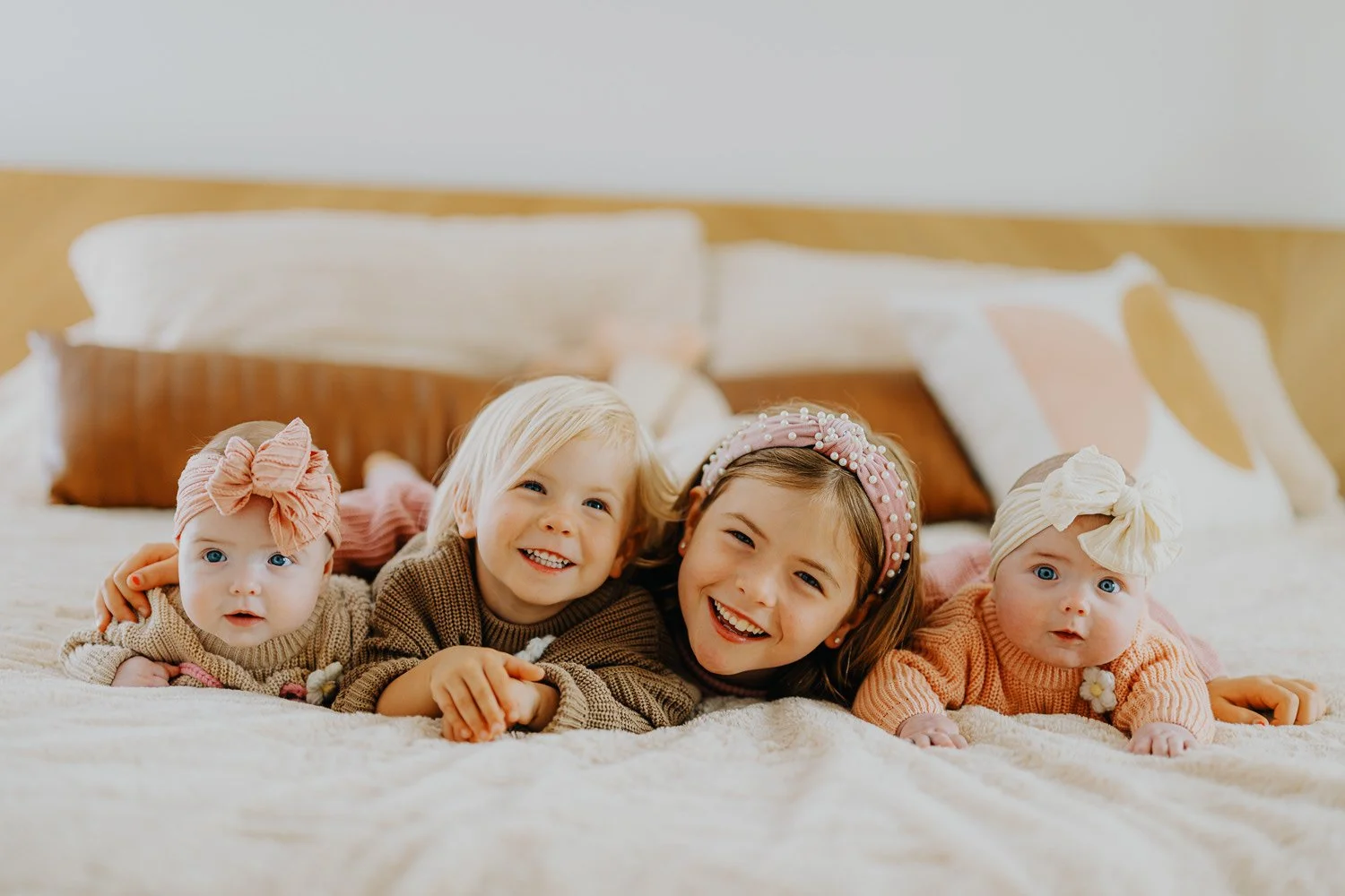 Children laughing and snuggling on a bed at home during a Lincoln family photography session.