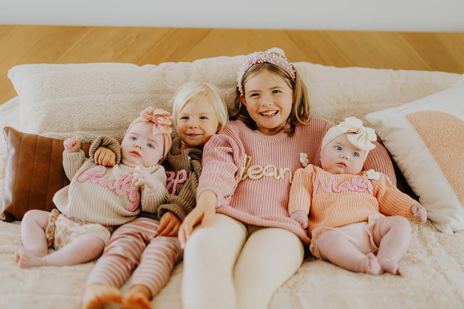 Lincoln Nebraska family photography of four siblings smiling on a bed.