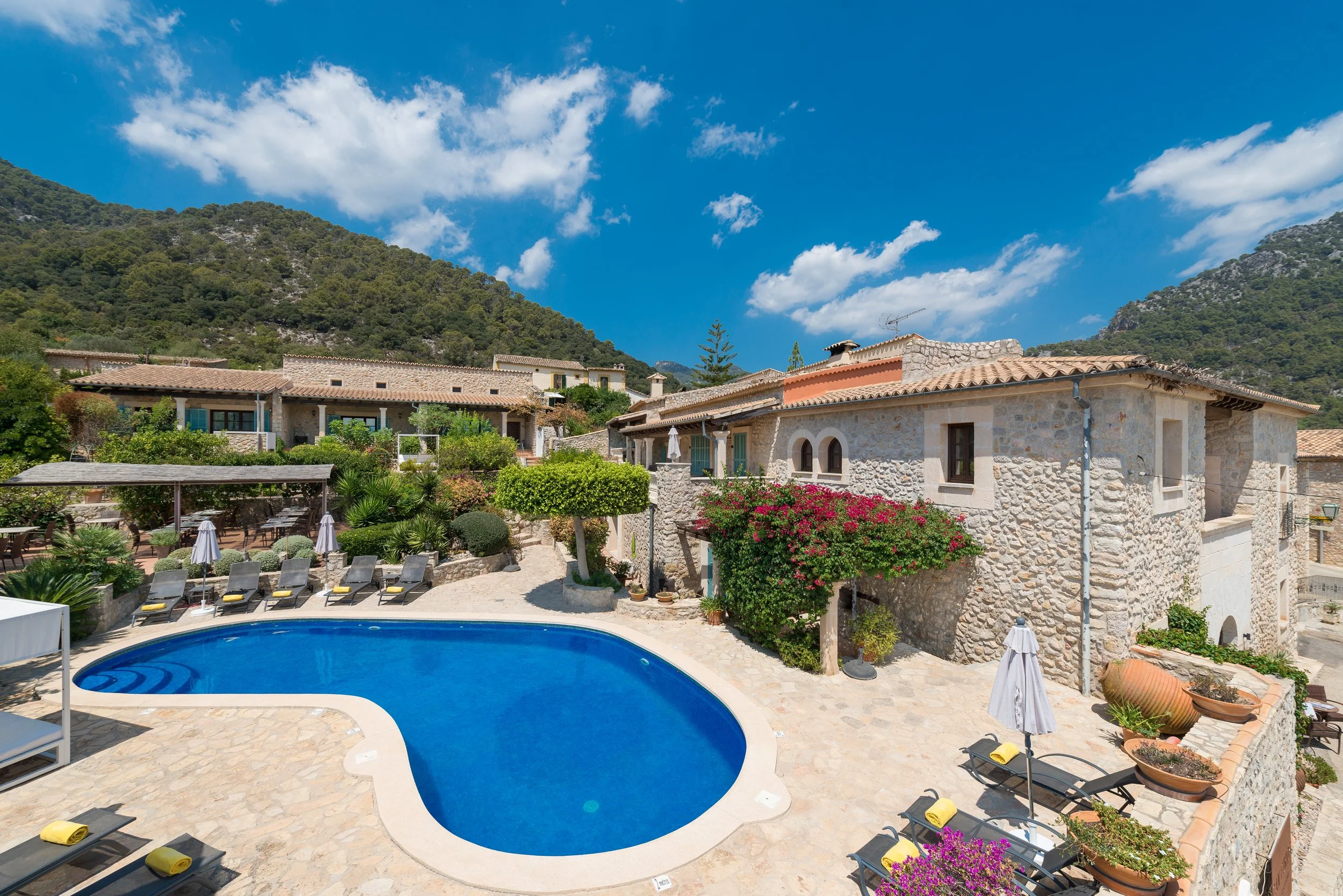 Mallorca, Spanien hotel med blå, rund pool og lave stenbygninger og rosenbuske.