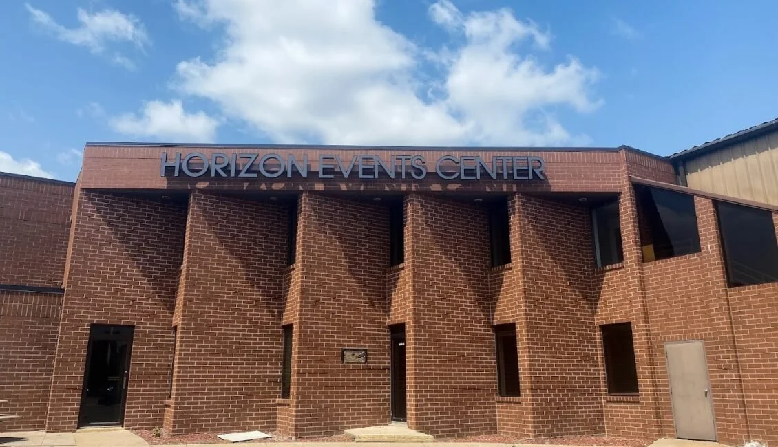 Brick building with a sign that reads 'Horizon Events Center' and a partly cloudy sky above.