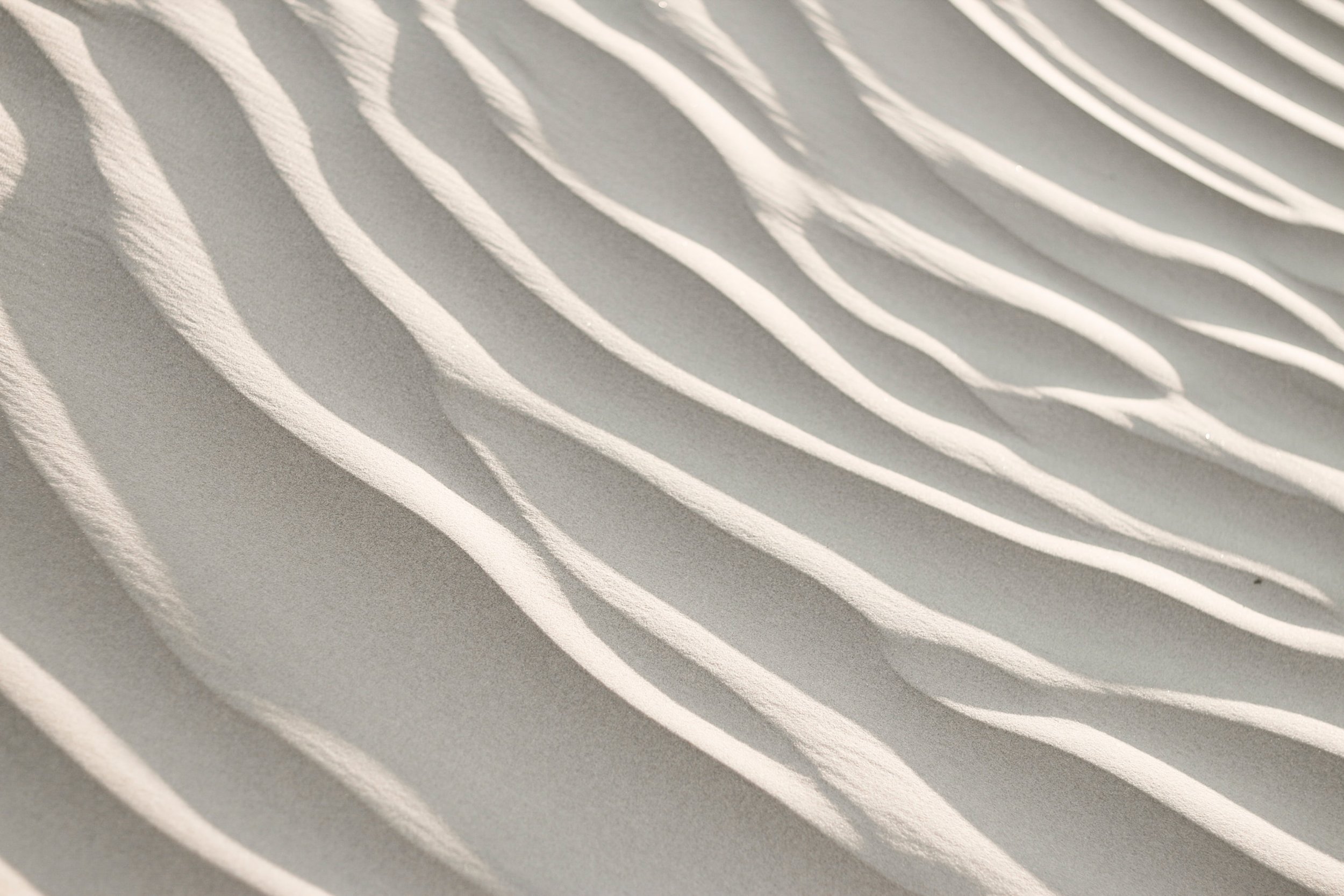 Close-up of white sand dunes with rippled patterns.
