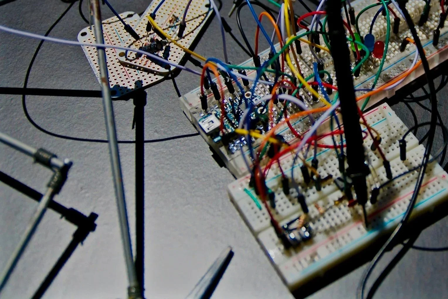 A close-up view of a complex electronic circuit setup with numerous wires, breadboards, and a circuit board on a table.