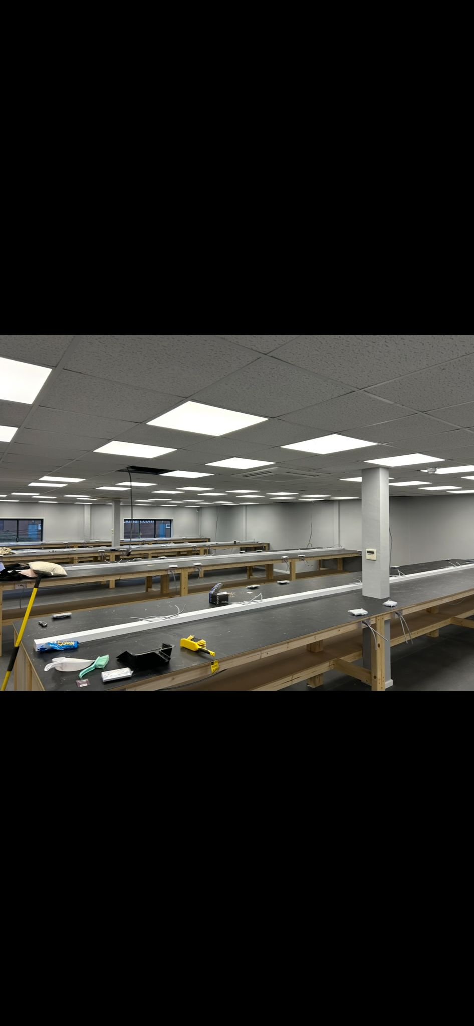 Empty workspace with long tables, tools, and equipment for assembly or manufacturing in an office or industrial setting.
