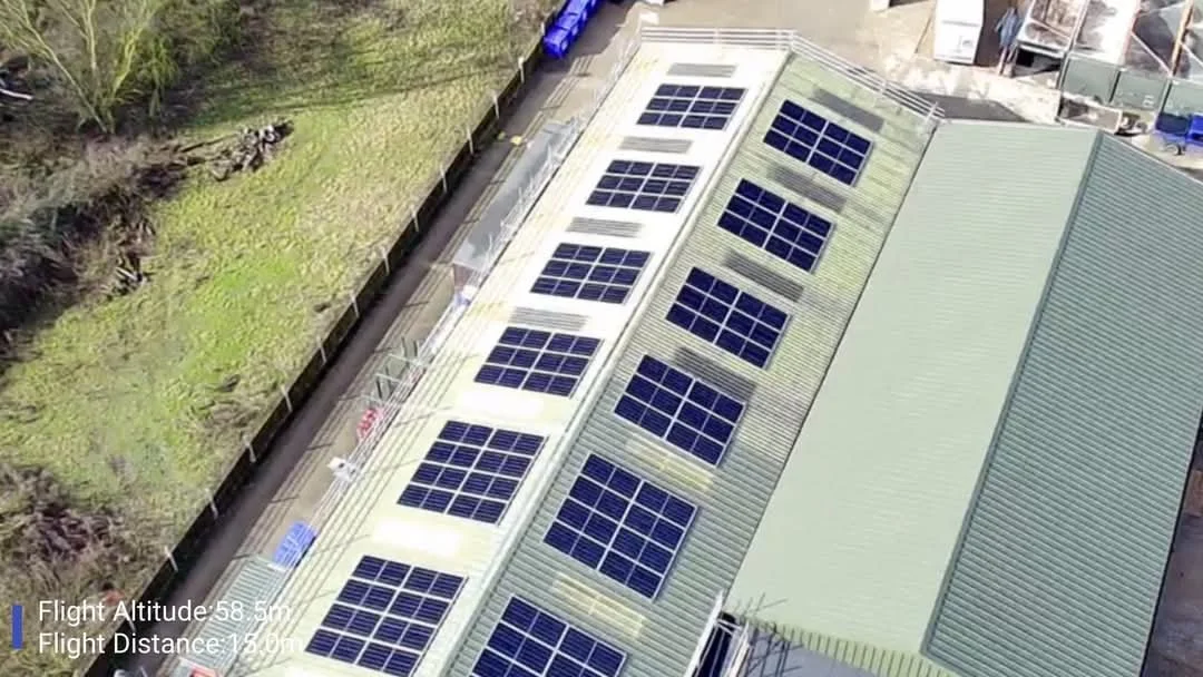 A building with a green metal roof fitted with multiple solar panels.