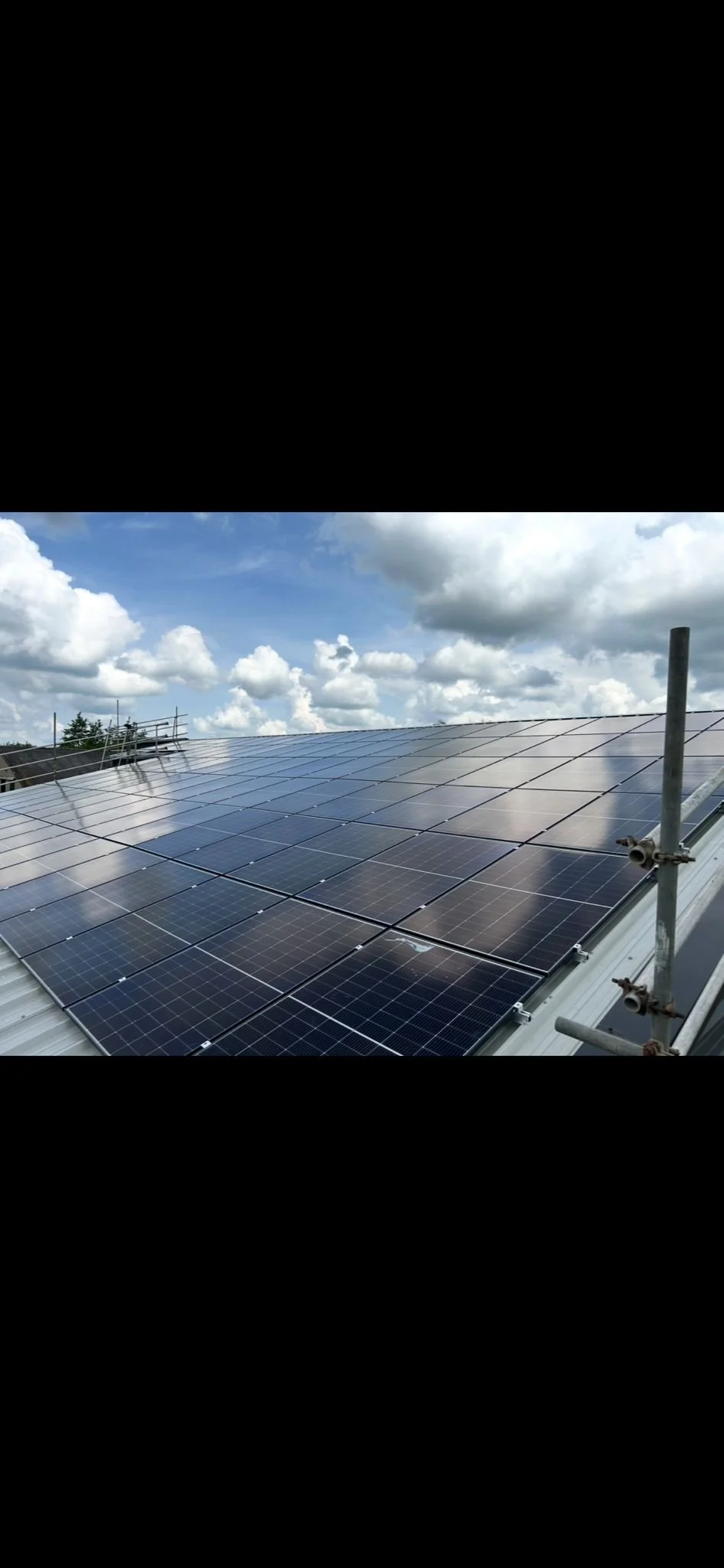 Solar panels installed on a rooftop under a partly cloudy sky.