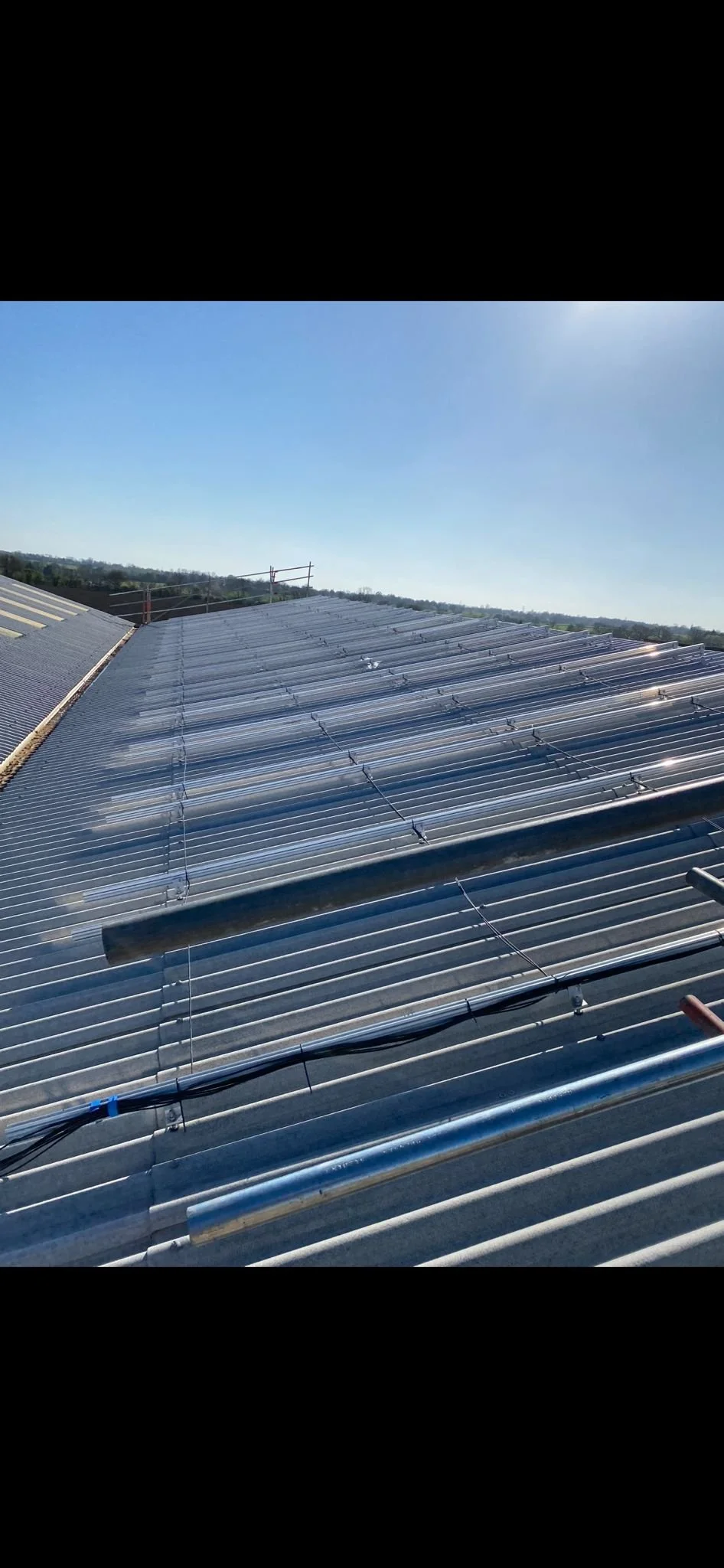Metal roof with solar panels installed on it, under a clear blue sky.