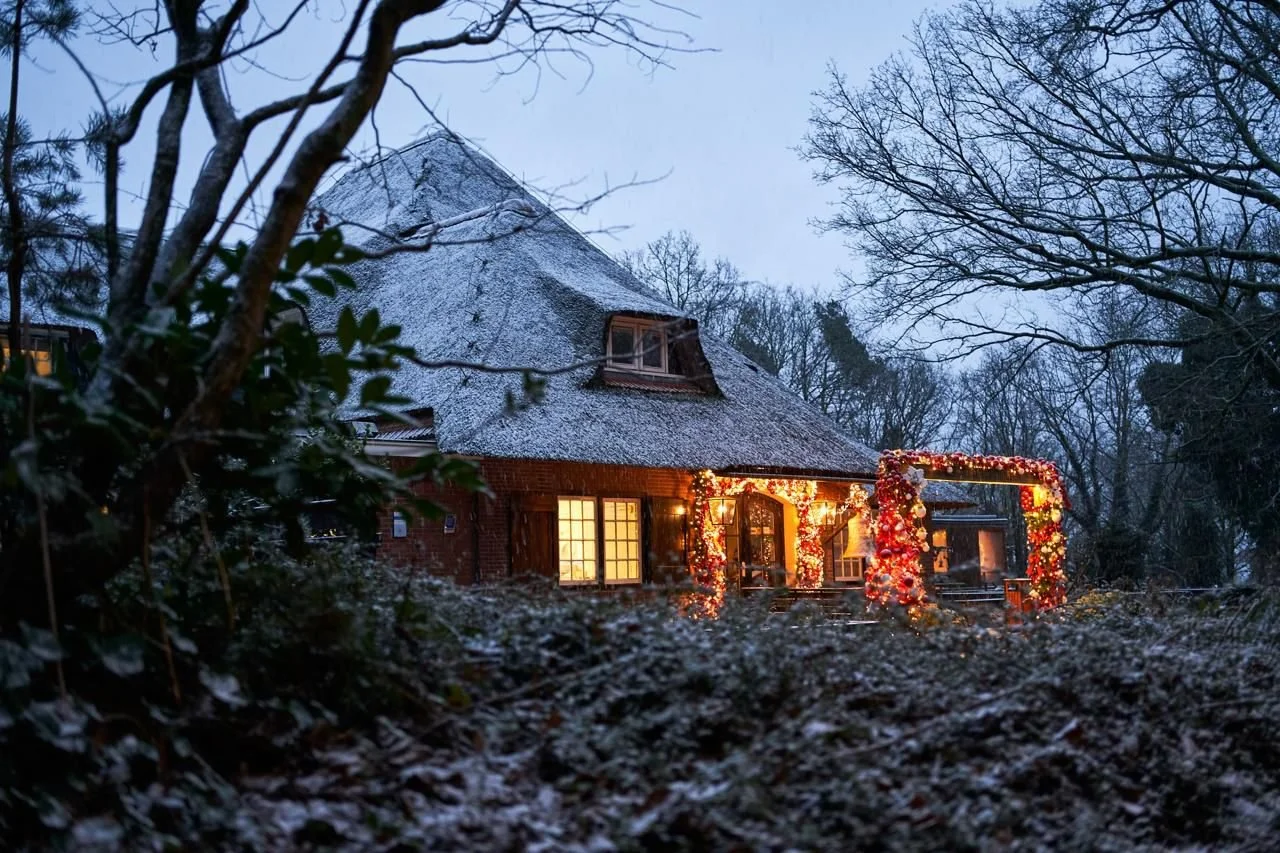 Vooraanzicht van het pand met kerstversiering en sneeuw op het dak