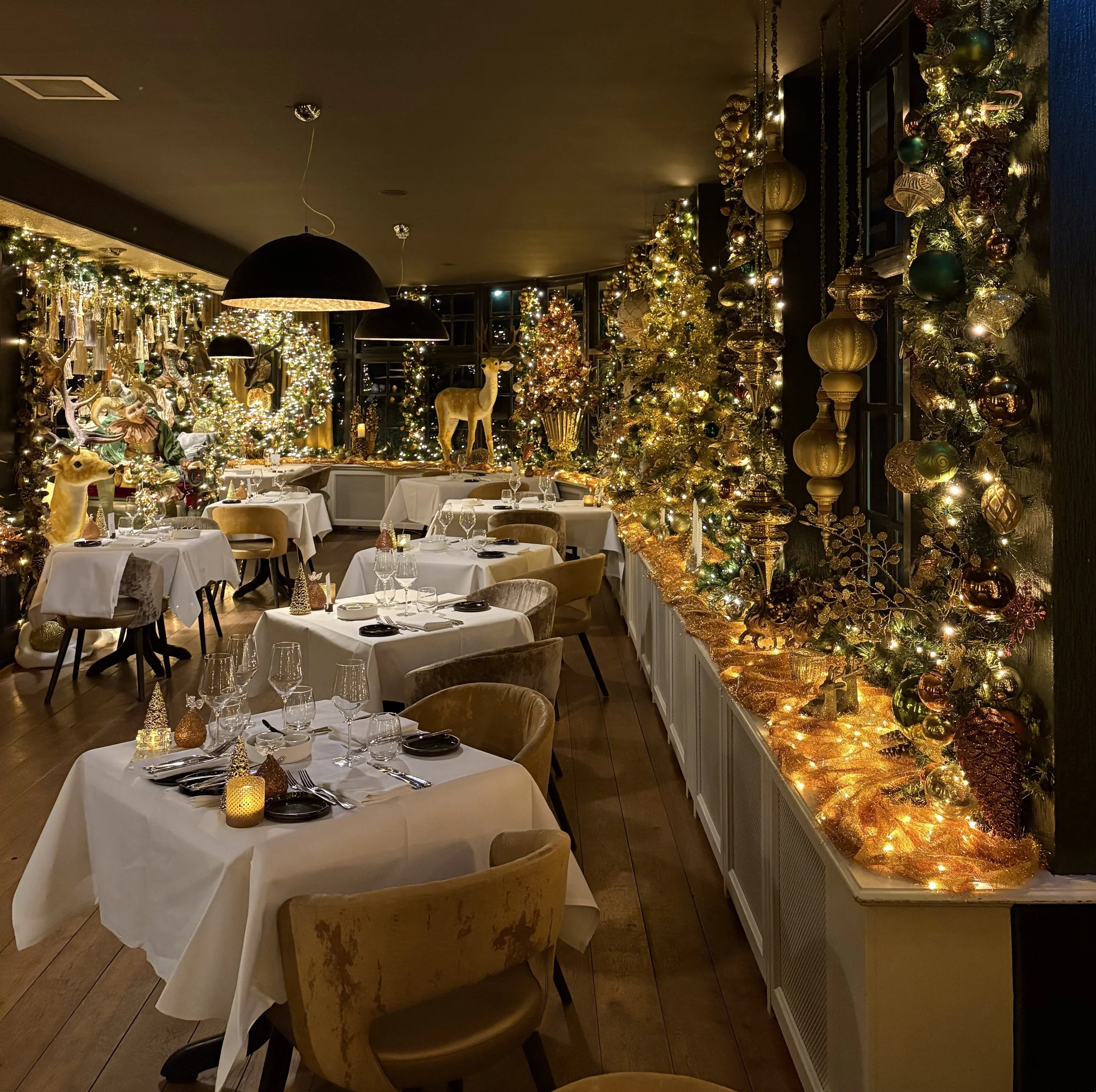 Restaurant totaal versierd in Kerstsferen. Veel kerstverlichting en kerstballen. Tafels feestelijk gedekt.