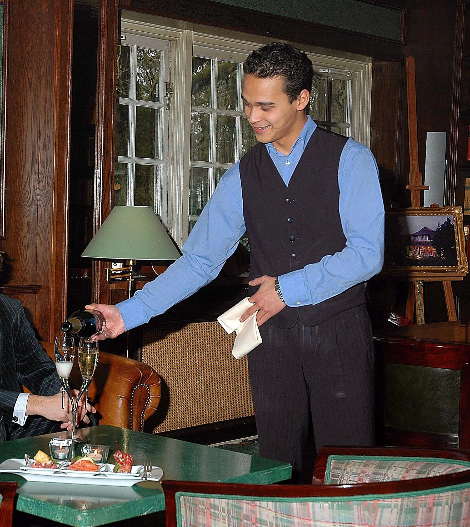 Medewerker schenkt champagne uit aan tafel