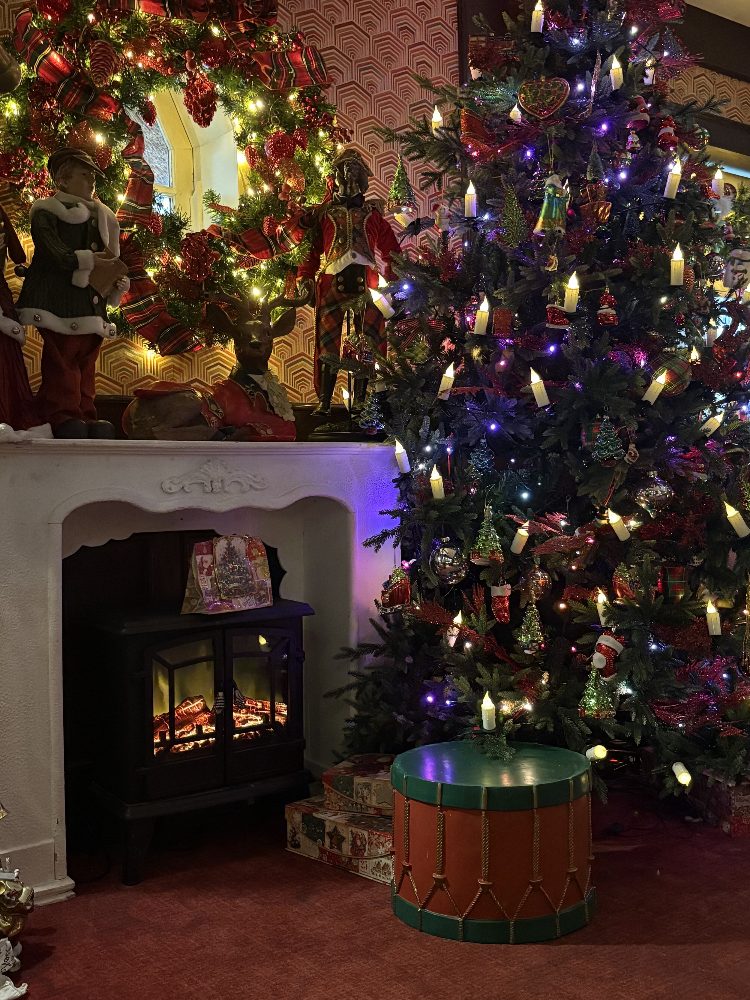 een openhaard met kerstboom vol met kerstversiering