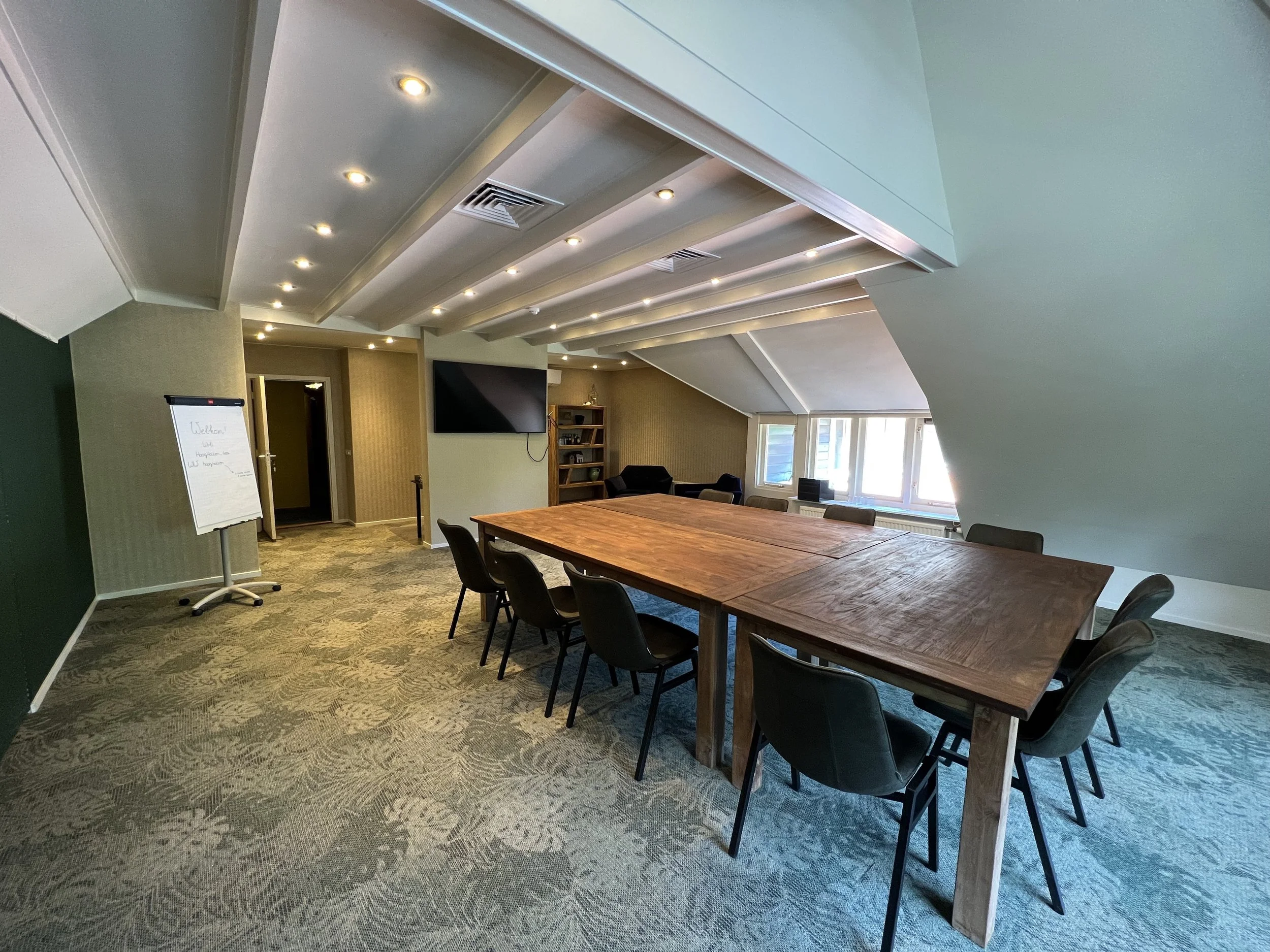 Vergaderruimte met houten tafel en scherm