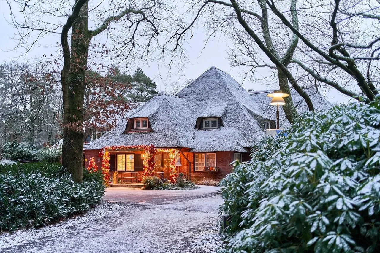 Buitenaanzicht van hotel versierd met kerstversiering, rode kerstballen en bedekt met sneeuw