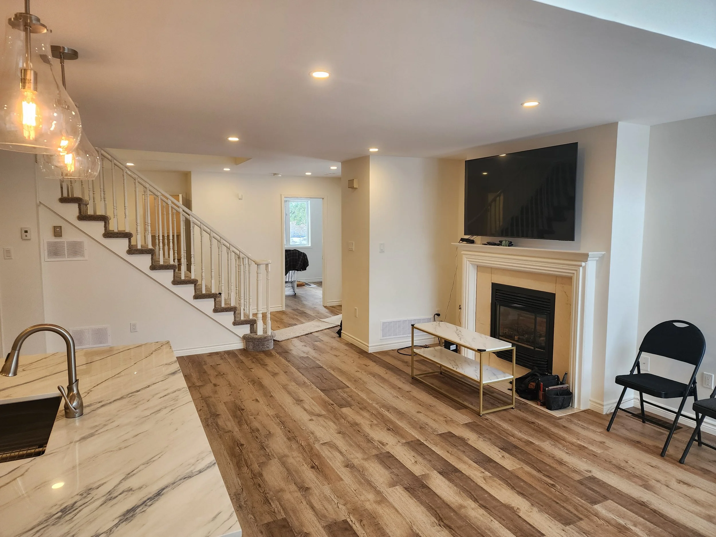open-concept-living-room-kitchen-fireplace-staircase-gravenhurst-muskoka-renovation.jpg