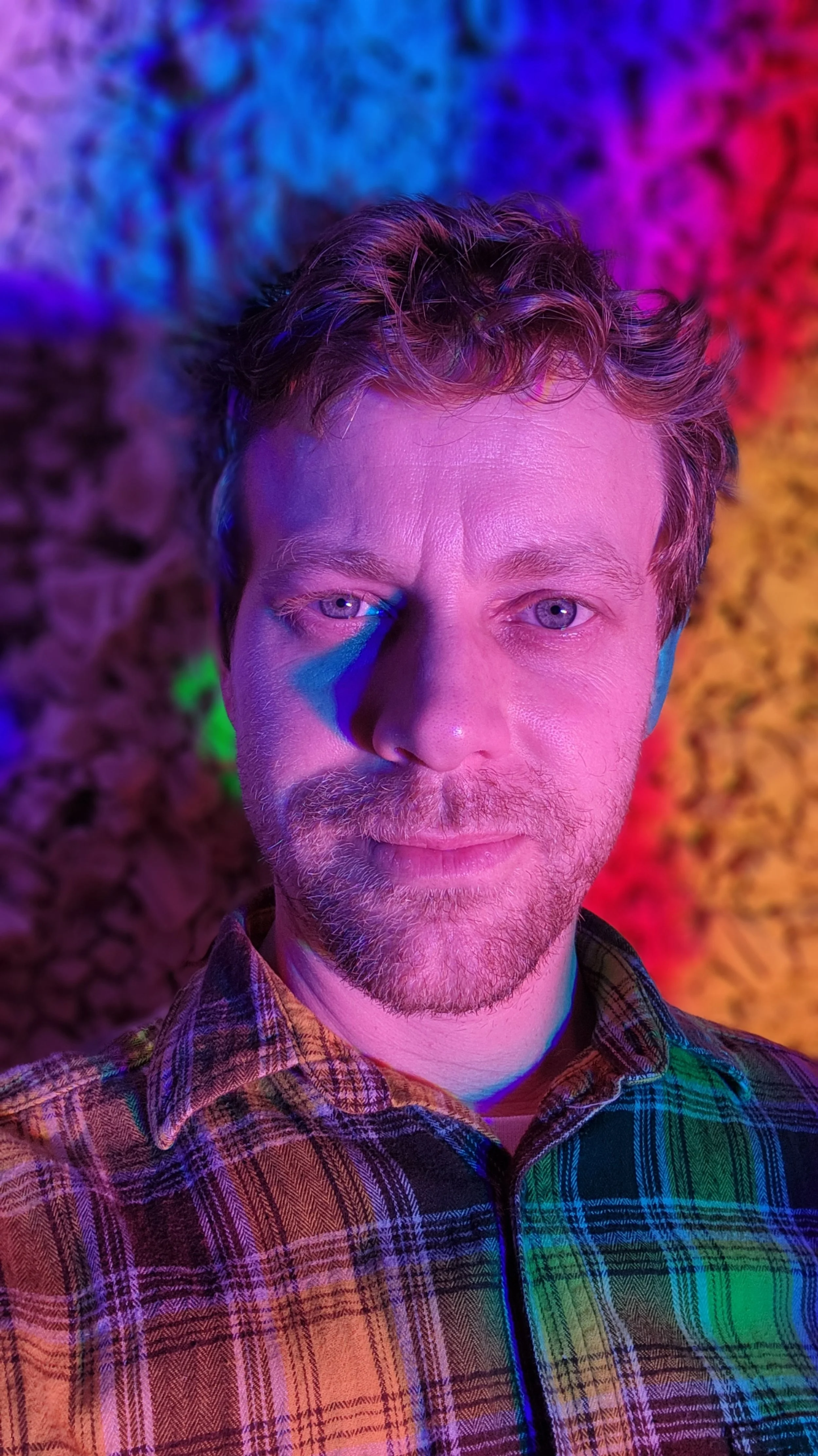 Musician Eric Frank a.k.a. Franko of Rhino's Brother looking into camera in front of rainbow textured background