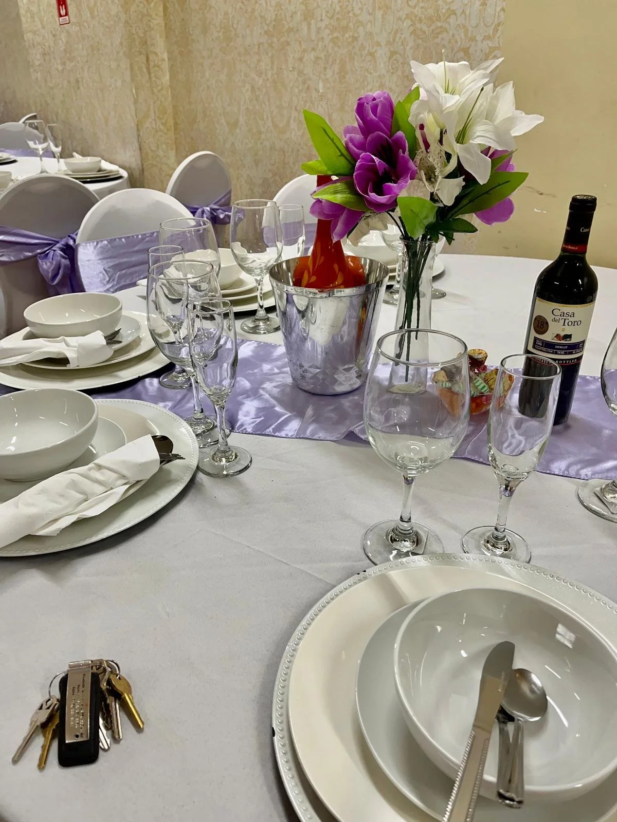 Table decorated in white and lavender, complete with utensils, wine, and flowers