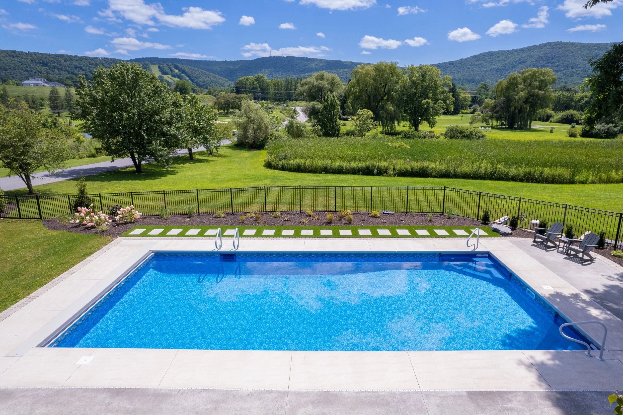 Backyard pool overlooking a green valley and distant mountains.