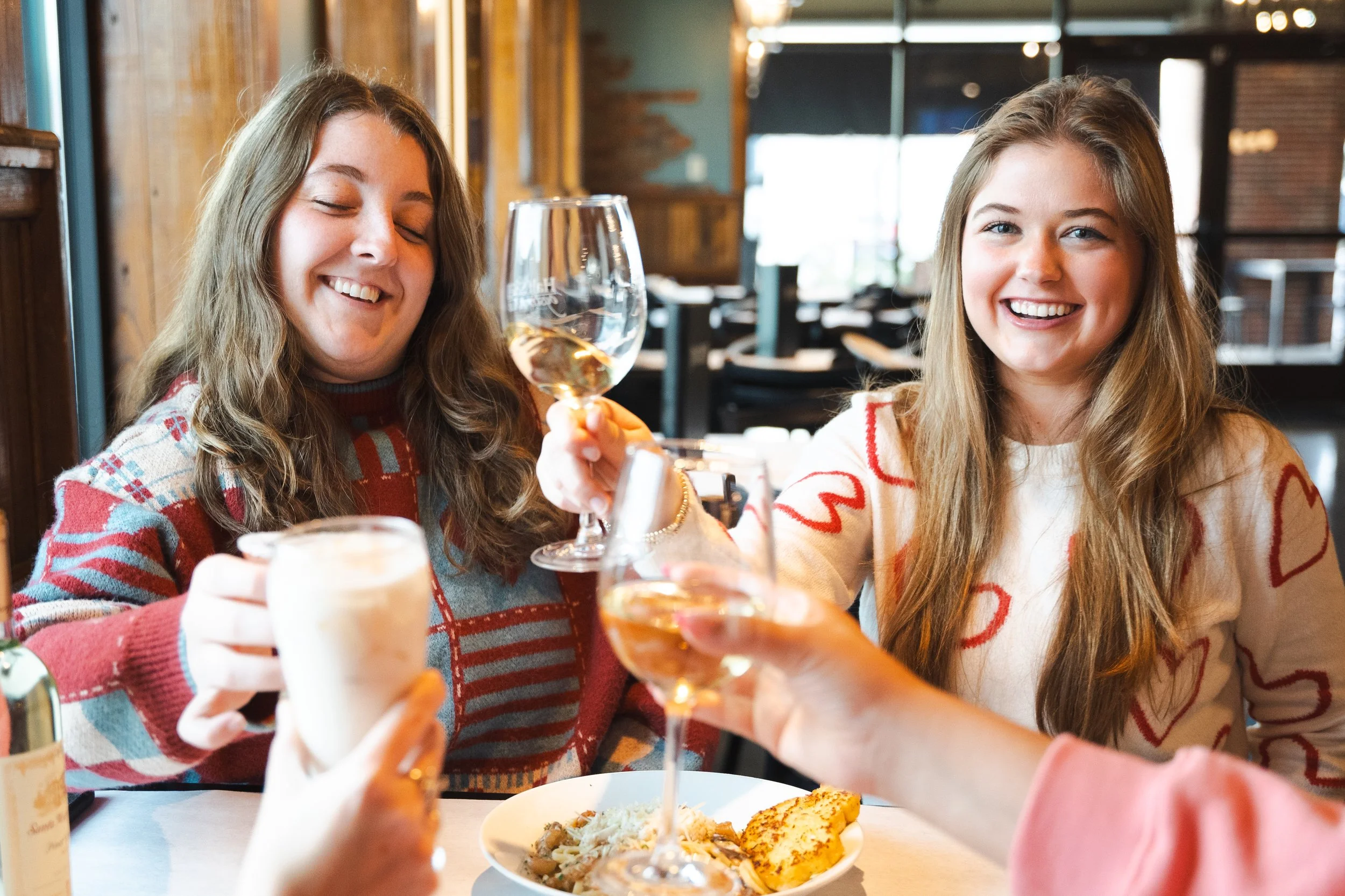 Two young women celebrating with wine glasses and oysters at a table at Half Shell Oyster House