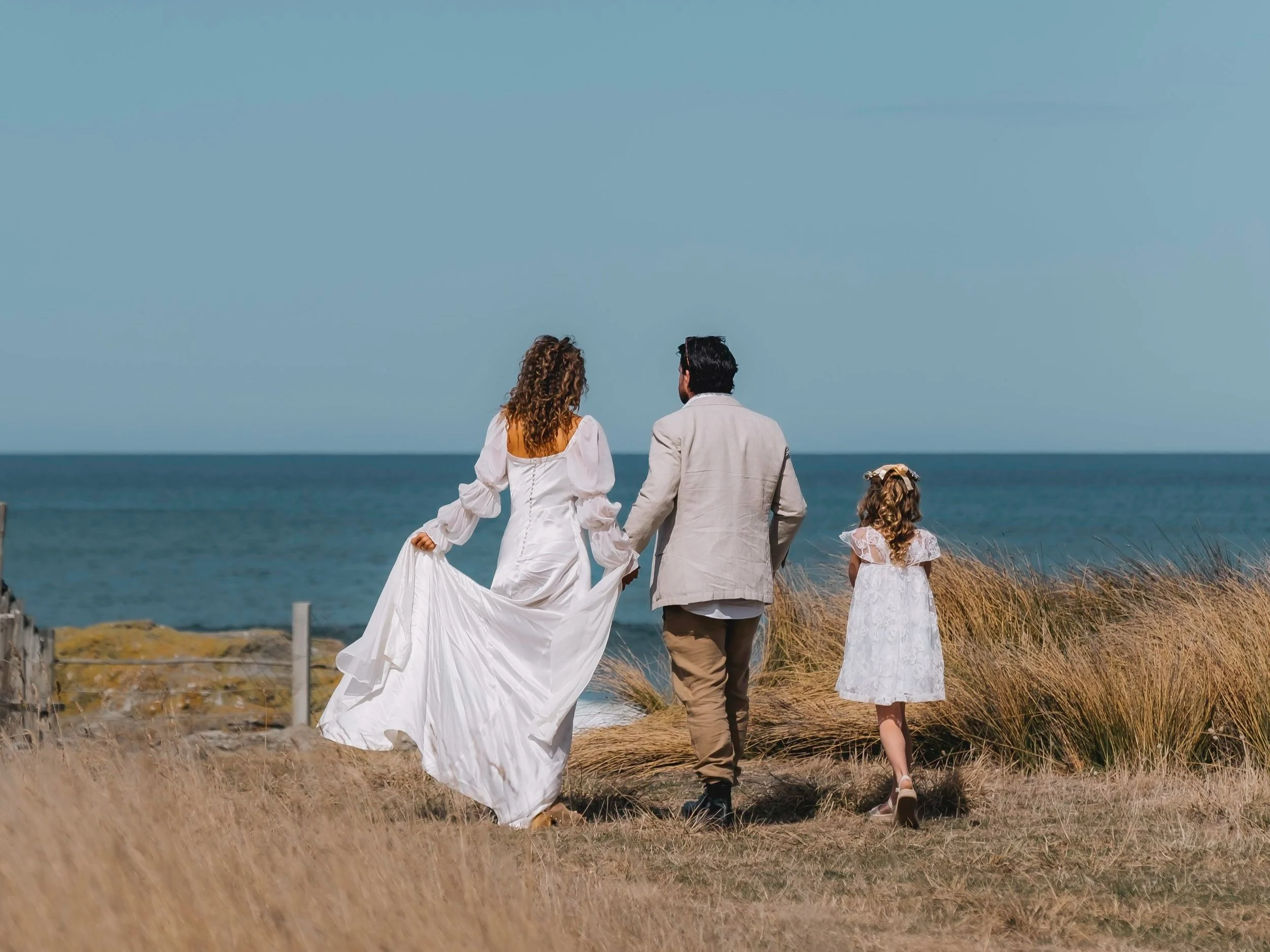 Troy and Claire from Tora Collective on their wedding day, walking along the beach together