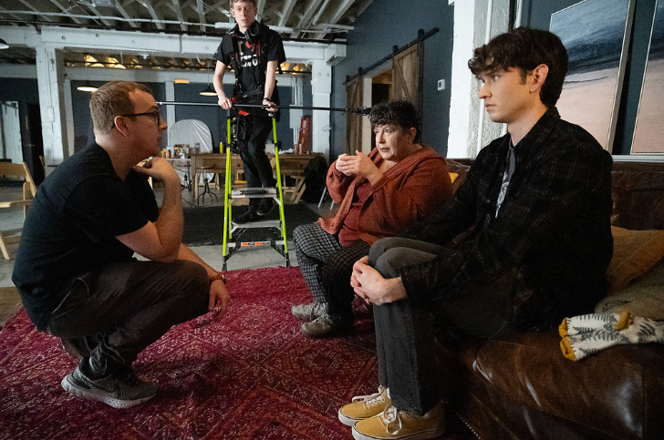 A director speaks to two actors on set