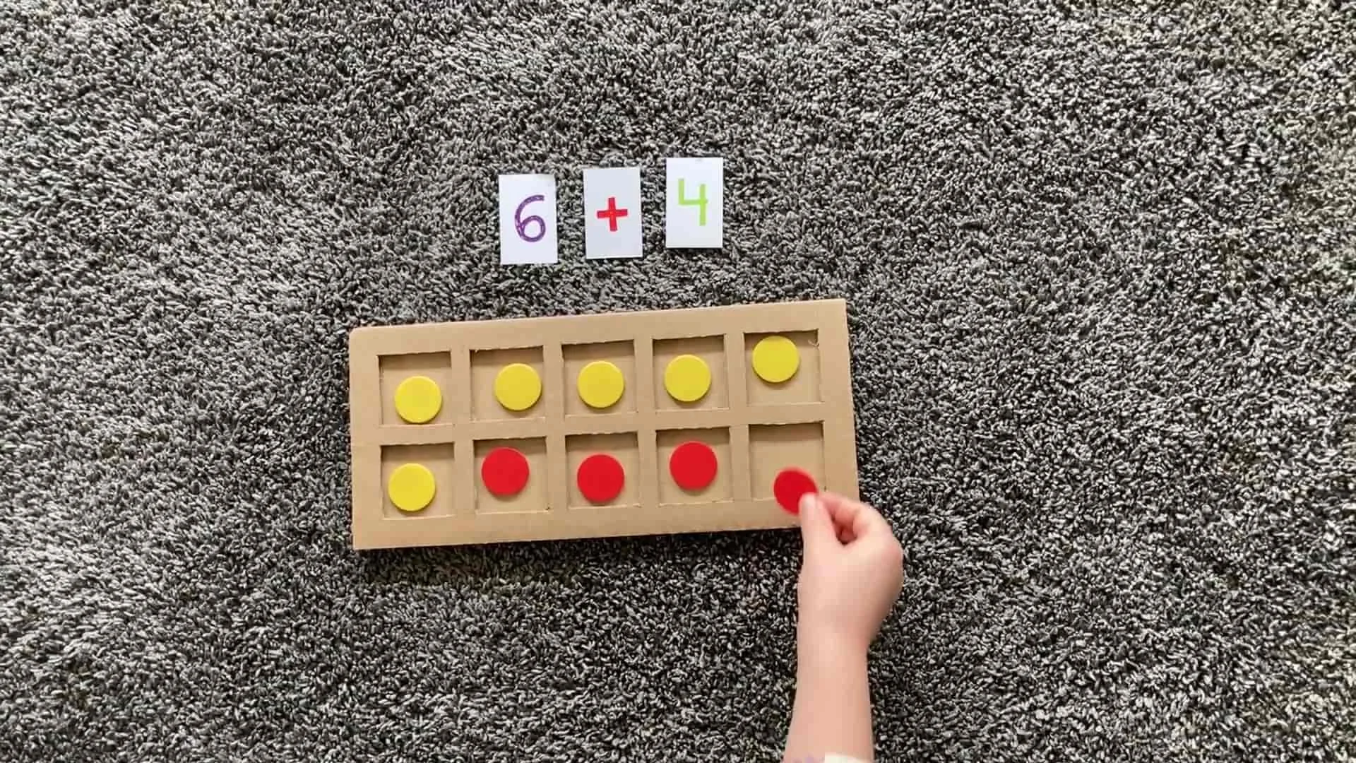 Cardboard tens frame with a maths problem and a child solving it with counters