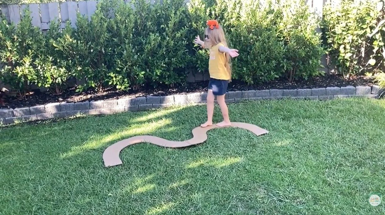 Child balancing on a beam made from cardboard that is curved