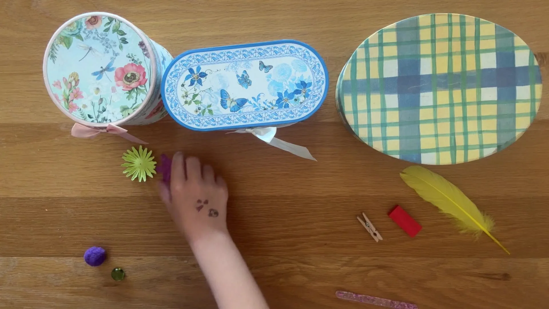 3 boxes with lids on and a child placing items in front that they think is in the box.
