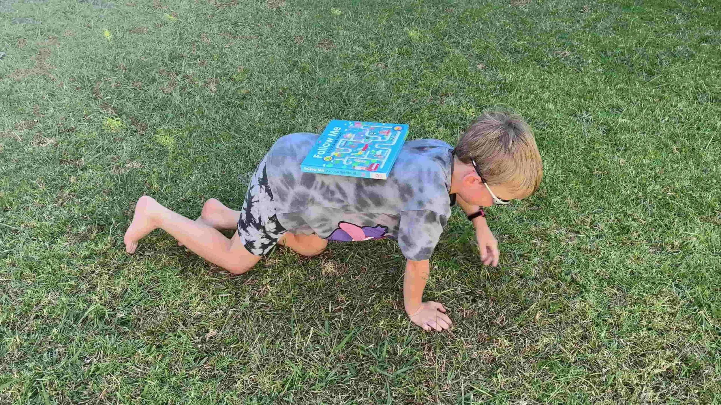 Child crawling with a book on their back.