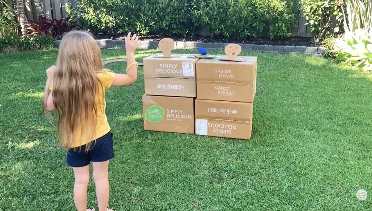 Child throwing bean bag at cardboard targets