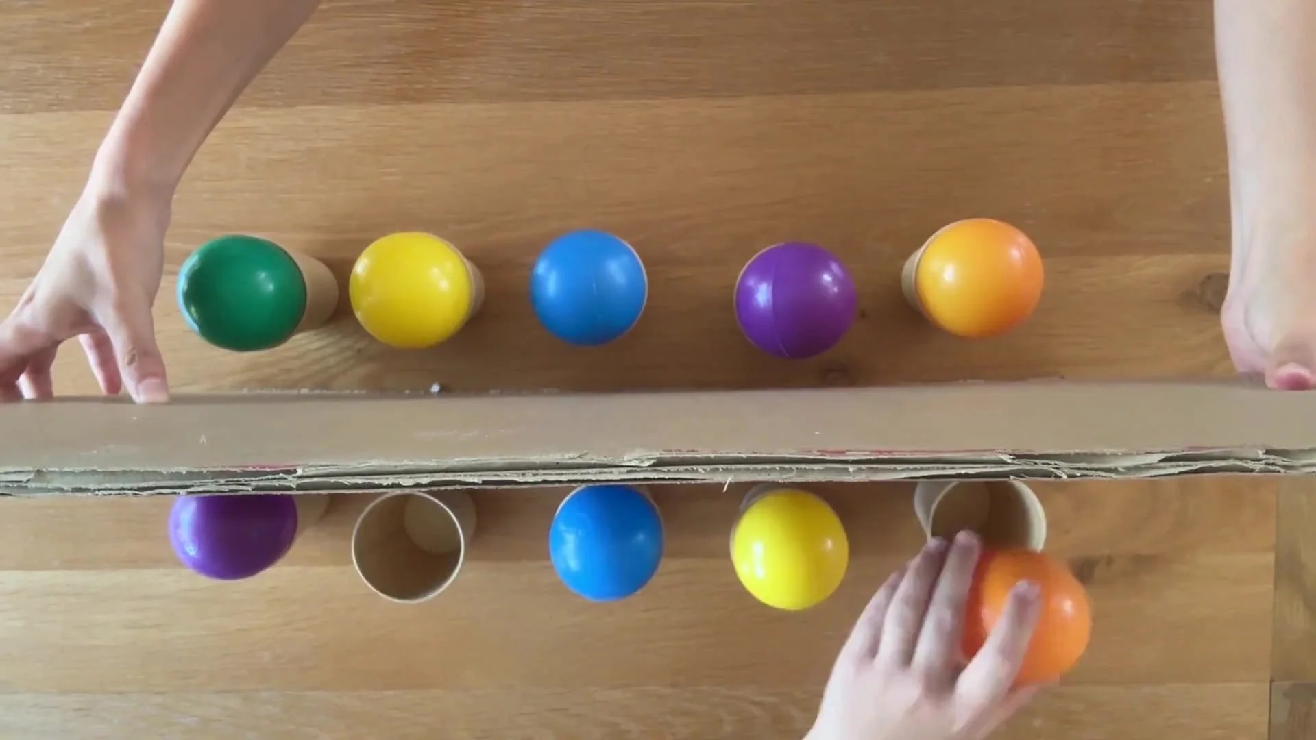 Balls on cups with a cardboard divider between two sets. The player is moving their balls to attempt to copy the sequence from memory.