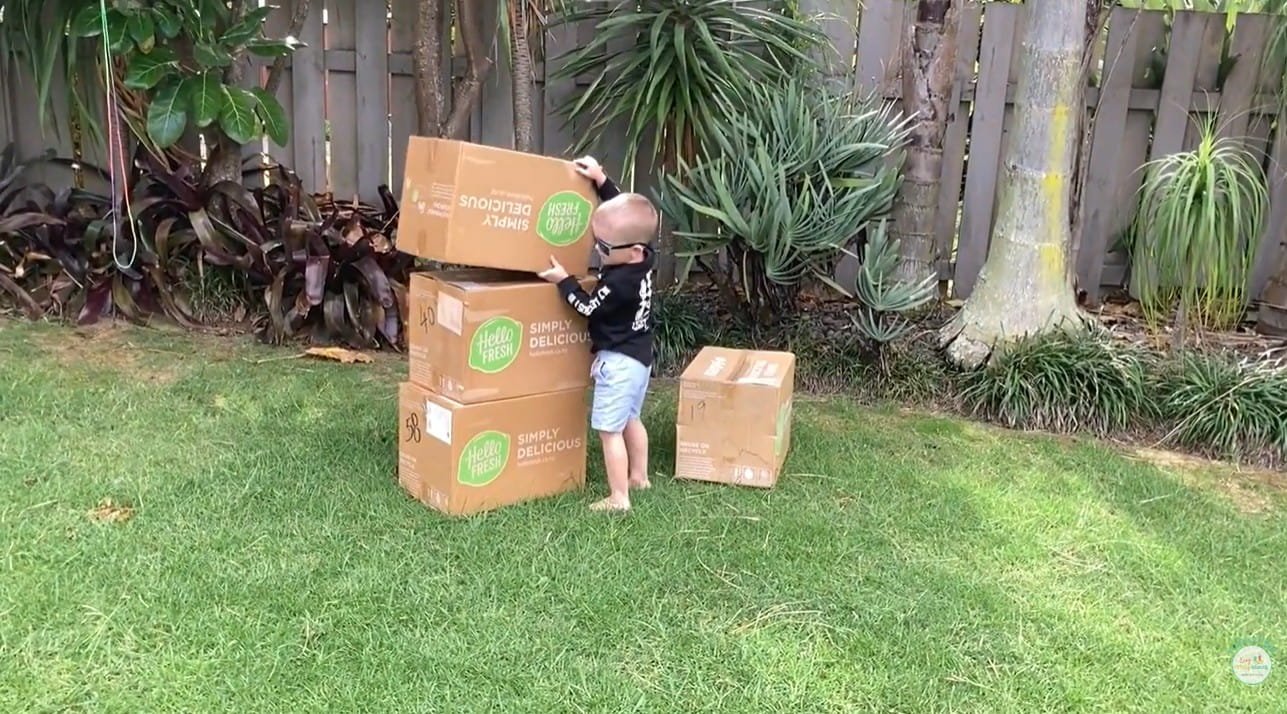 Child stacking cardboard boxes o make a tower