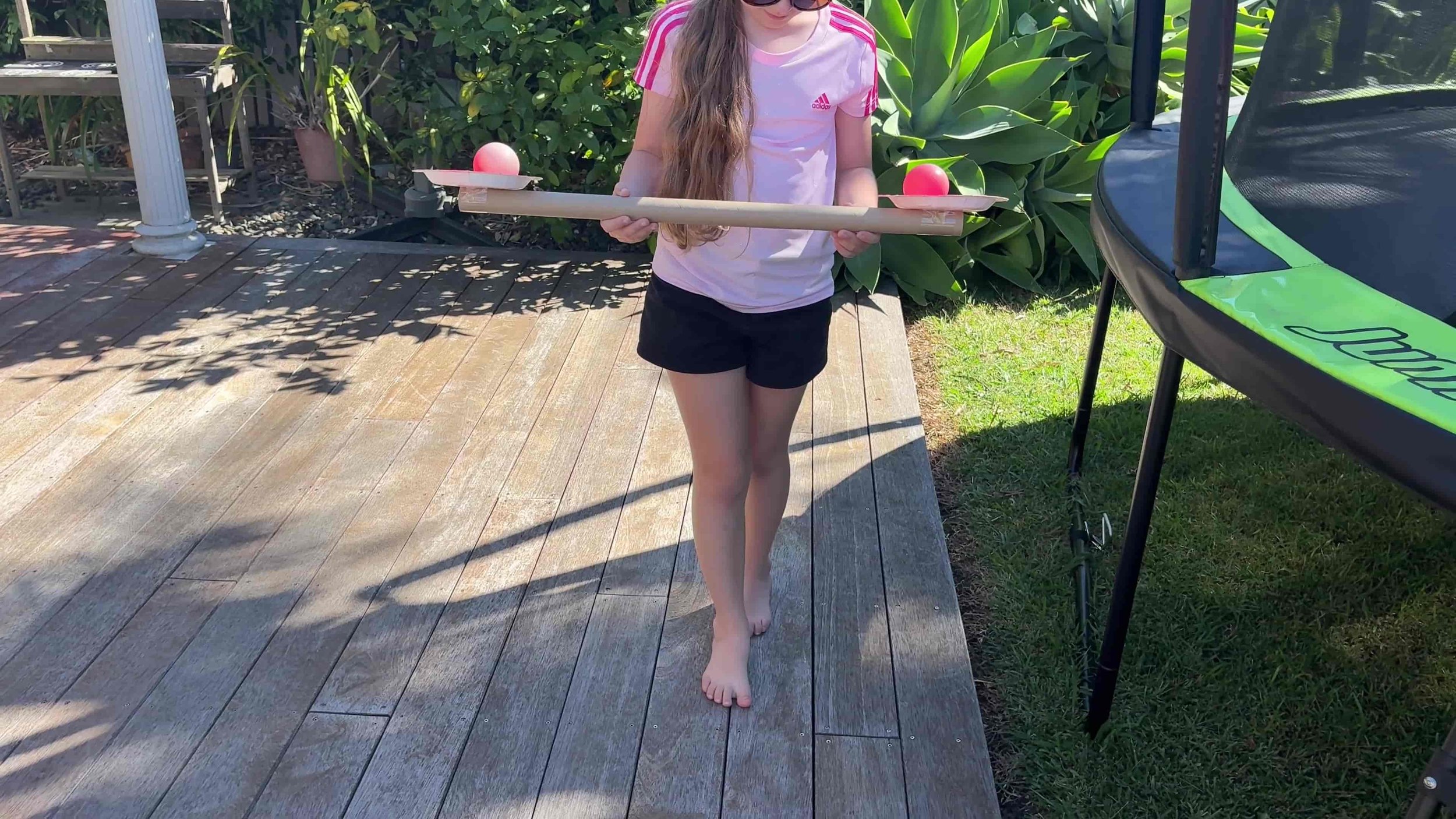 Child balancing with a tube and balls balanced and walking in a straight line