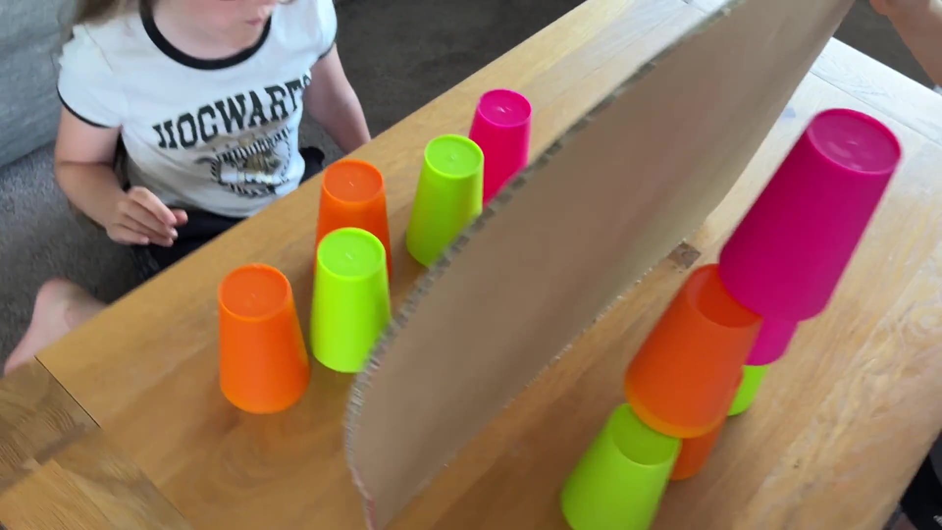 Child attempting to build a cup tower with a divider hiding the original tower pattern.