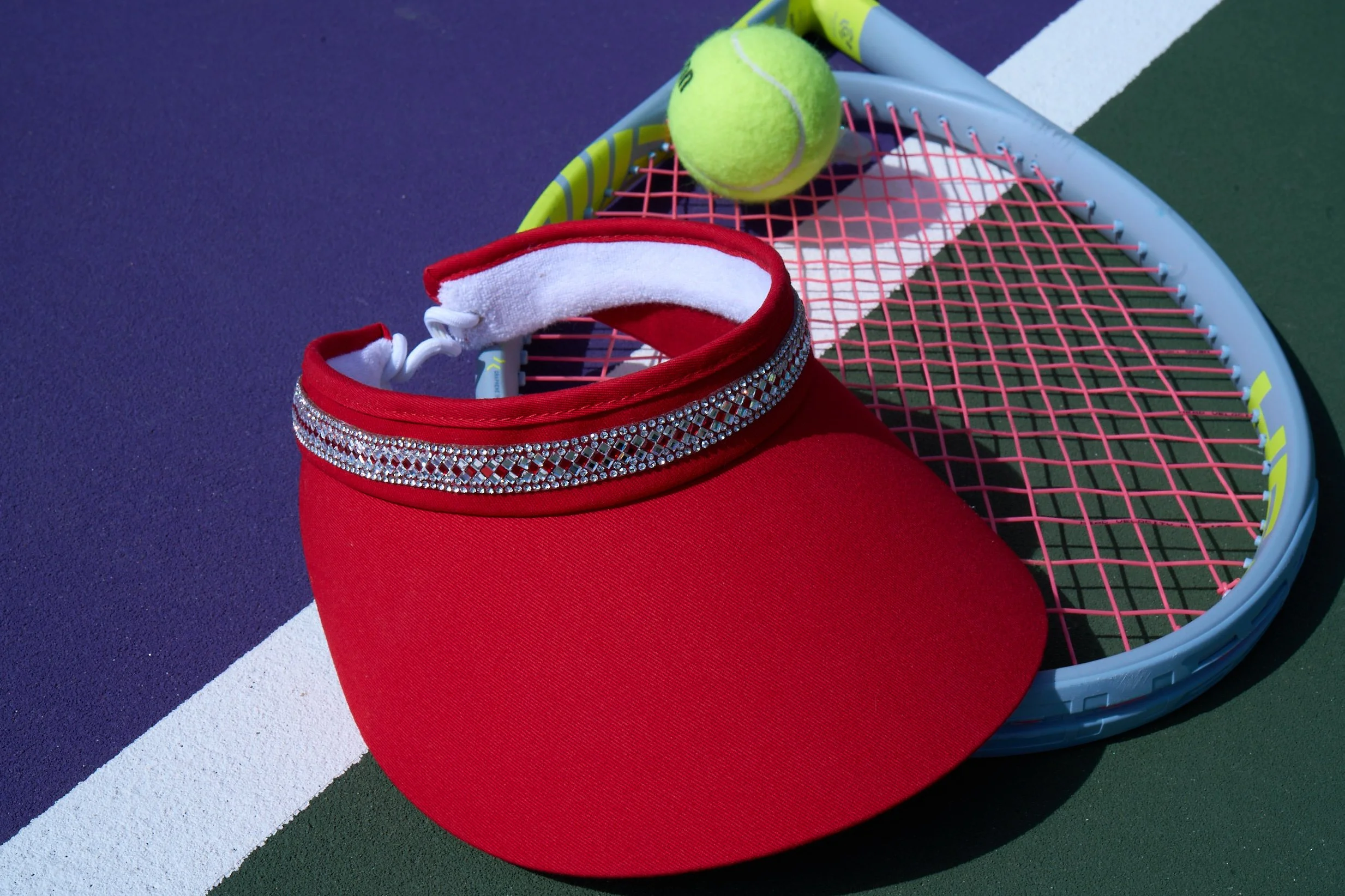 A red Swarovski crystal visor on the tennis court