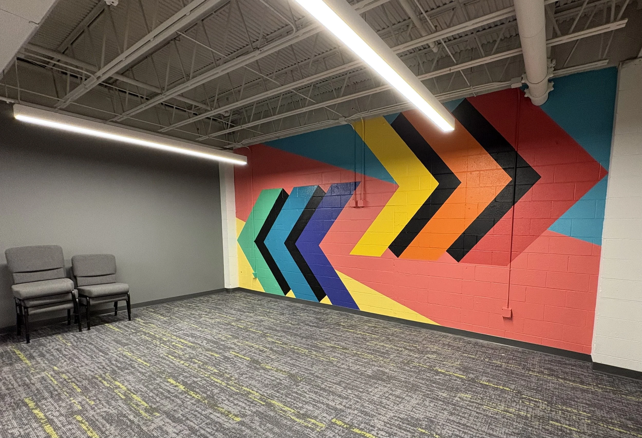 Colorful geometric arrows mural on cinderblock