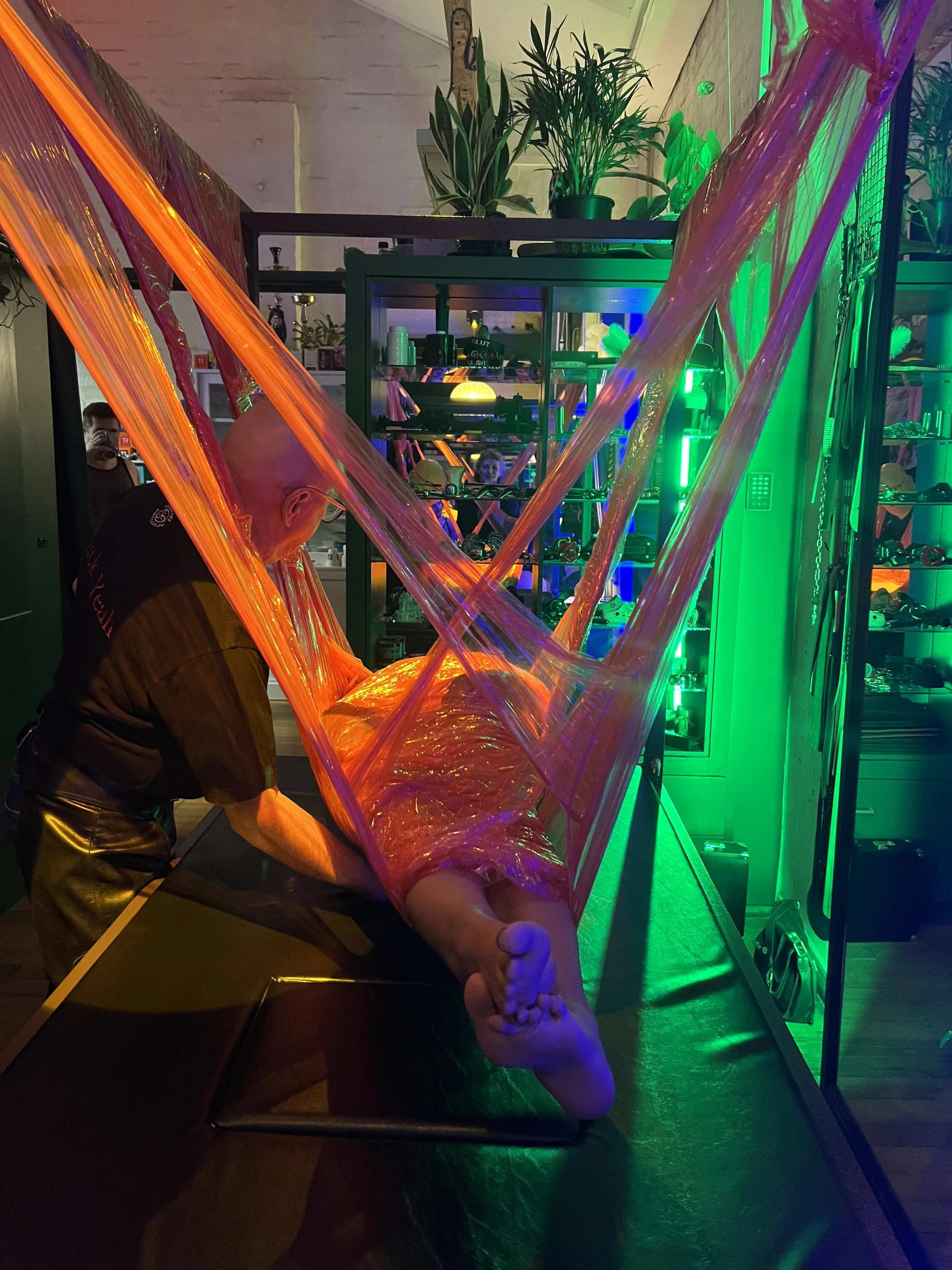 Person suspended in red saran wrap