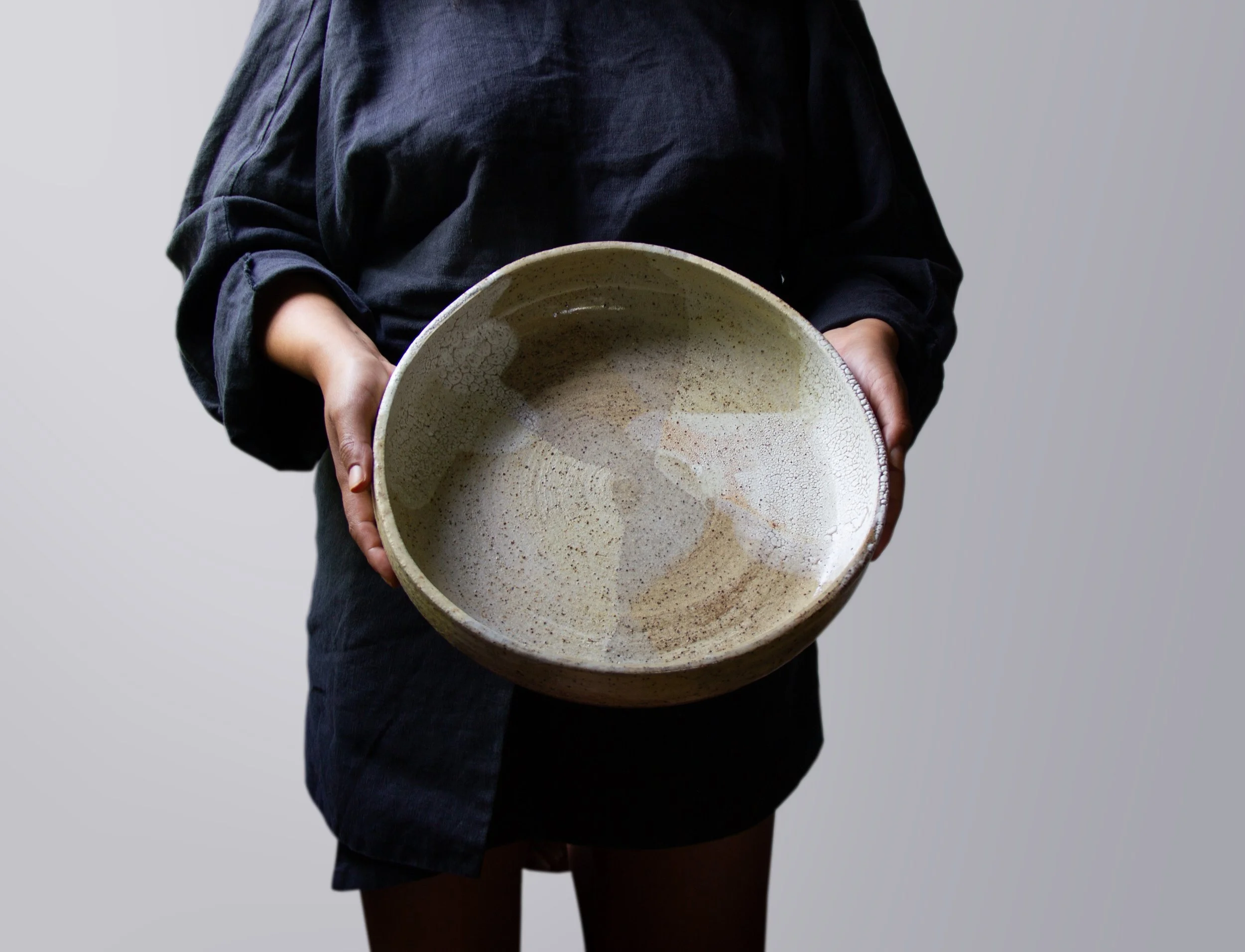 hands holding a large handmade pottery bowl