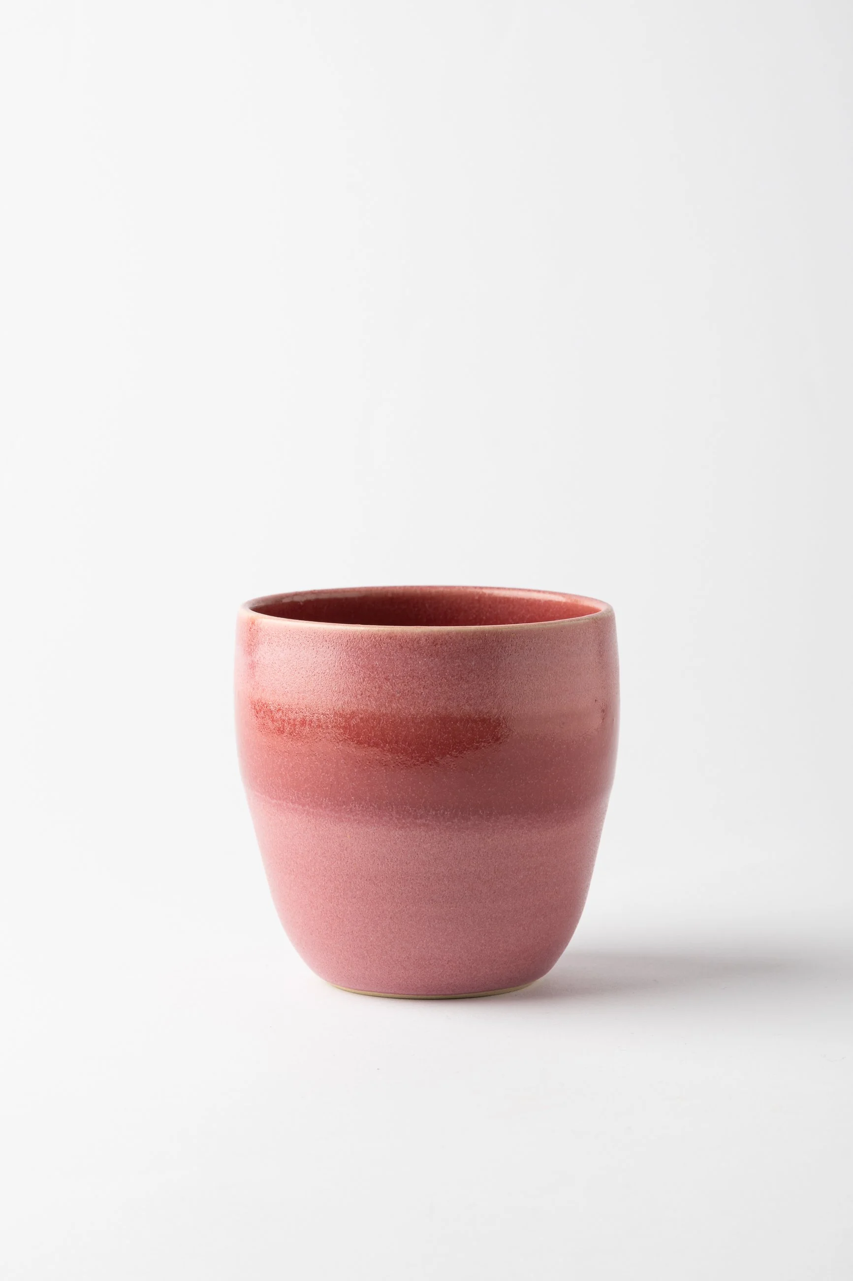 Handmade pink ceramic tumbler with layered matte and glossy glaze