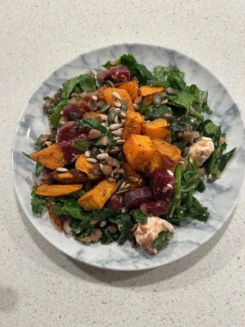 Linsesalat med bagte rødbeder, feta, grønne blade og ristede kerner på en marmoreret tallerken