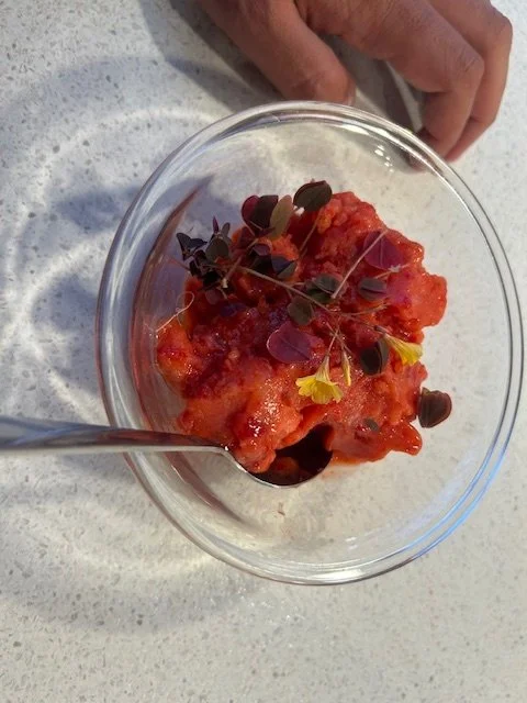 Jordbærsorbet uden ismaskine i en glasskål, pyntet med små blade og gule blomster