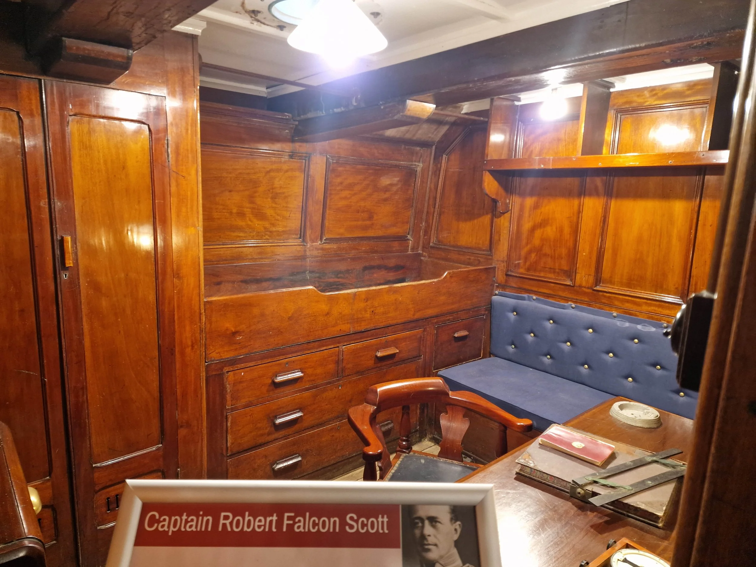 The captain's cabin - a fitted wardrobe, cabin bed, narrow sofa, and desk with chair. All, including the wood paneling, are in varnished wood.
