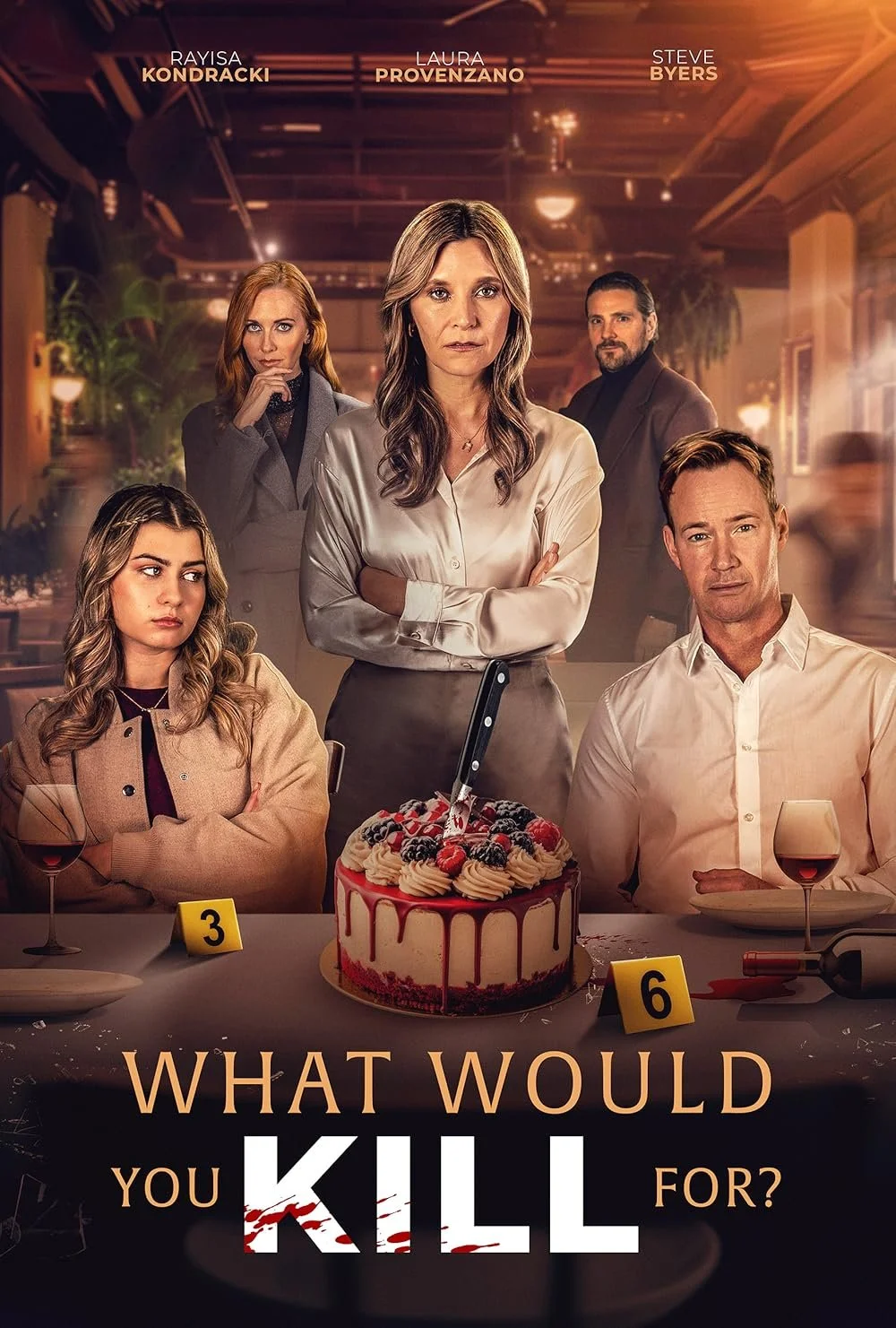 A blonde woman in her 40s stands with arms folded and an intense expression in front of a pavlova with a kitchen knife stabbed into it and red juice down the sides. She is surrounded by four other people, all with similarly serious expressions.