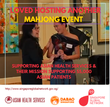Matchmaker Cassindy Hosts - Two women talking at a Mahjong event supporting Asian health services, with a banner behind them mentioning love, hosting, Mahjong, and supporting Asian patients.