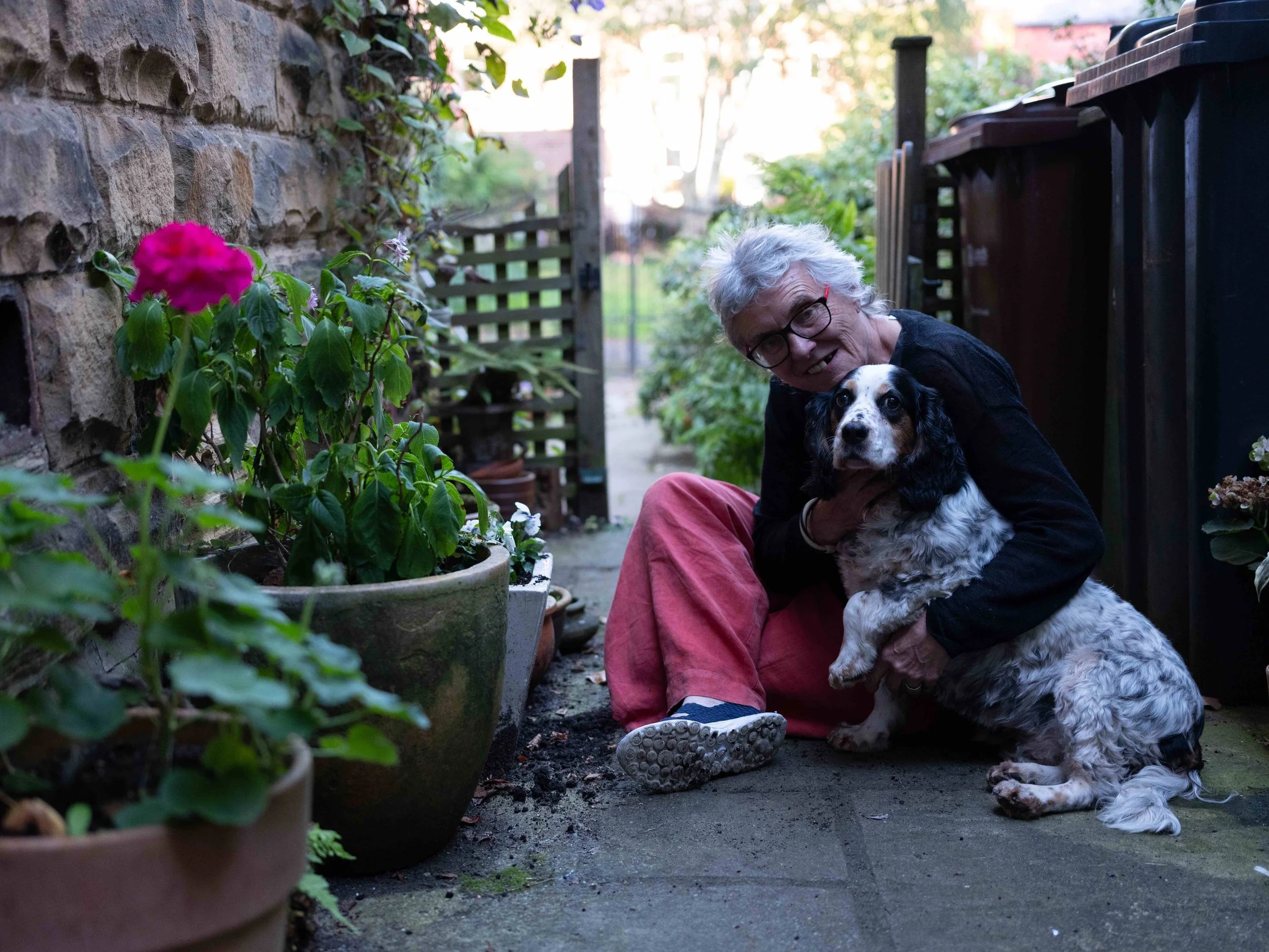 Image of happy elderly woman cuddling a dog outside