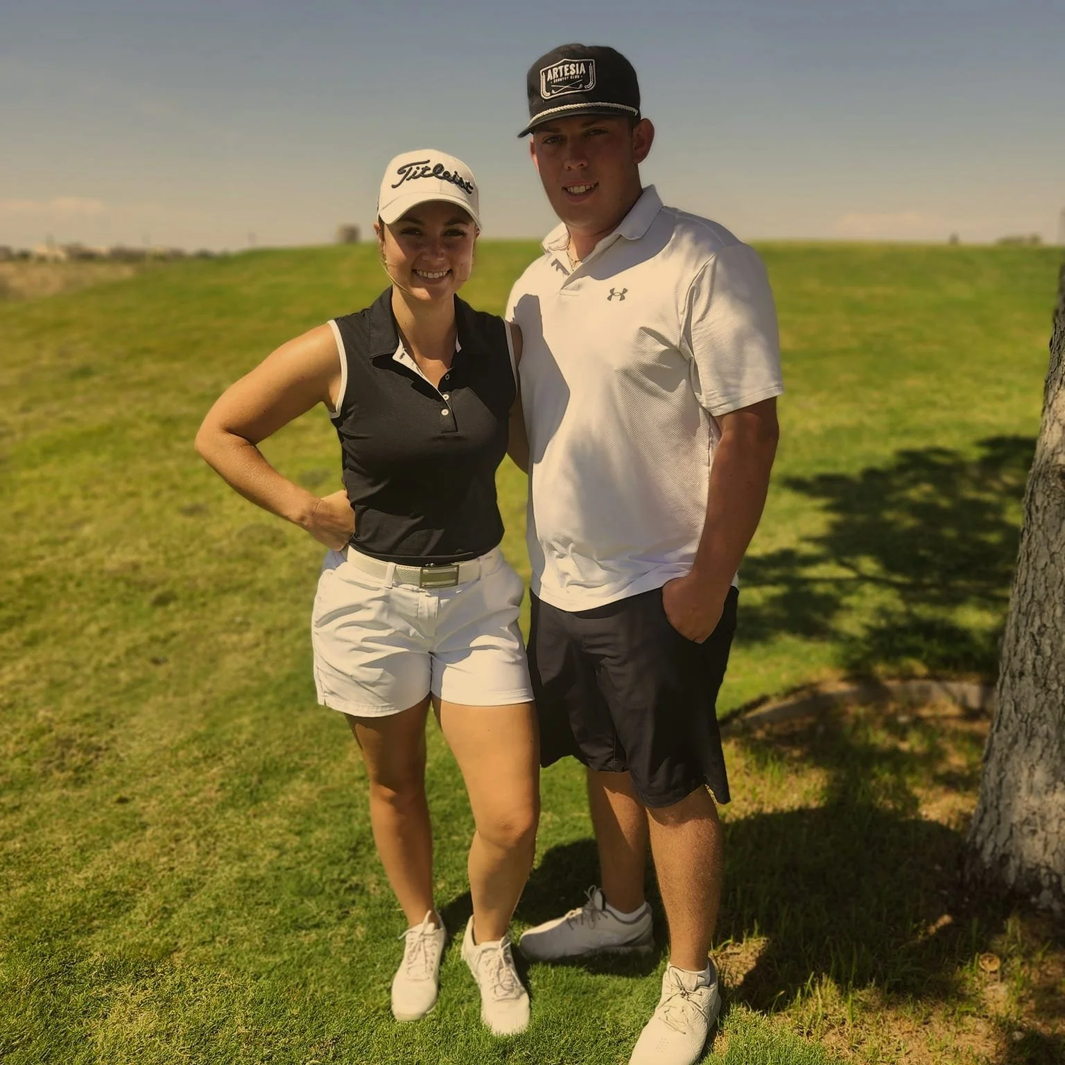 woman in shorts with a sleeveless golf shirt standing by man in shorts wearing golf shirt