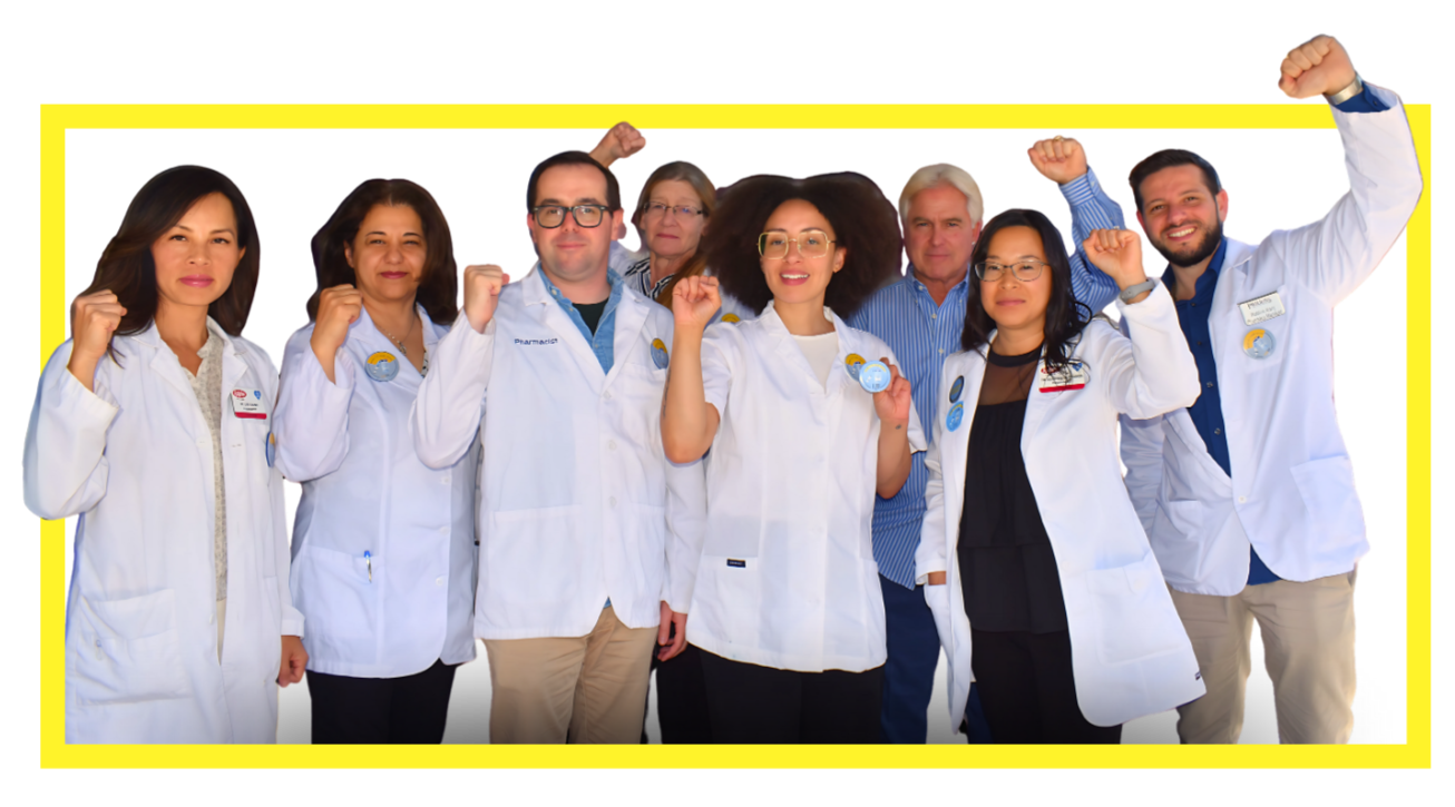 Group of diverse healthcare professionals and pharmacists in white lab coats celebrating with raised fists and smiles.