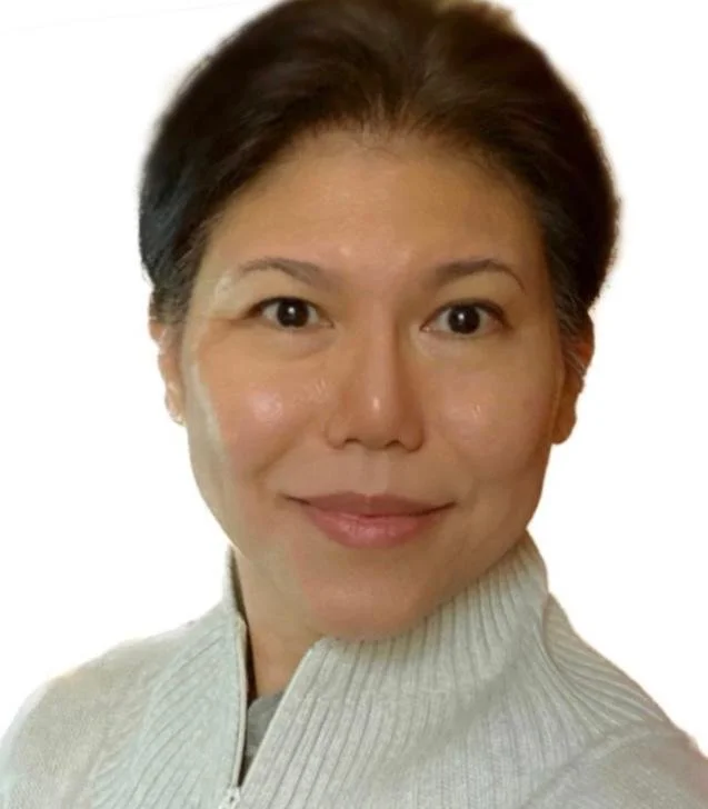 A woman with short dark hair smiling, wearing a light gray zip-up sweater, against a plain white background.